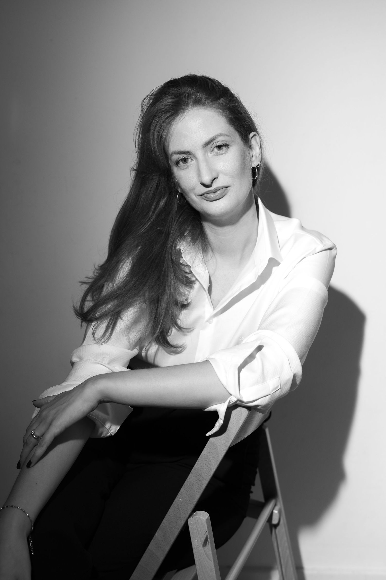 A black and white photographic series shows a figure in a white shirt posing dramatically against a light background.