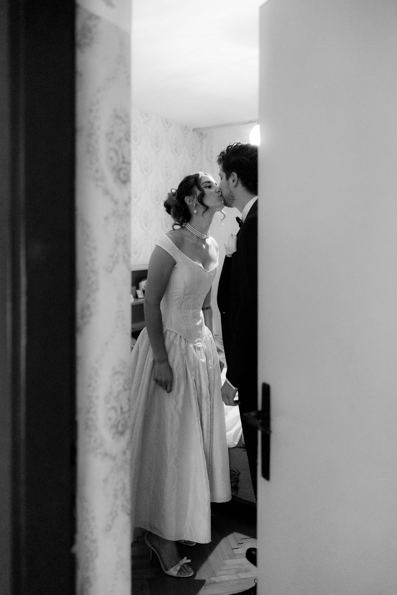 Black and white candid wedding moments captured in a hallway with elegant lighting and decor.