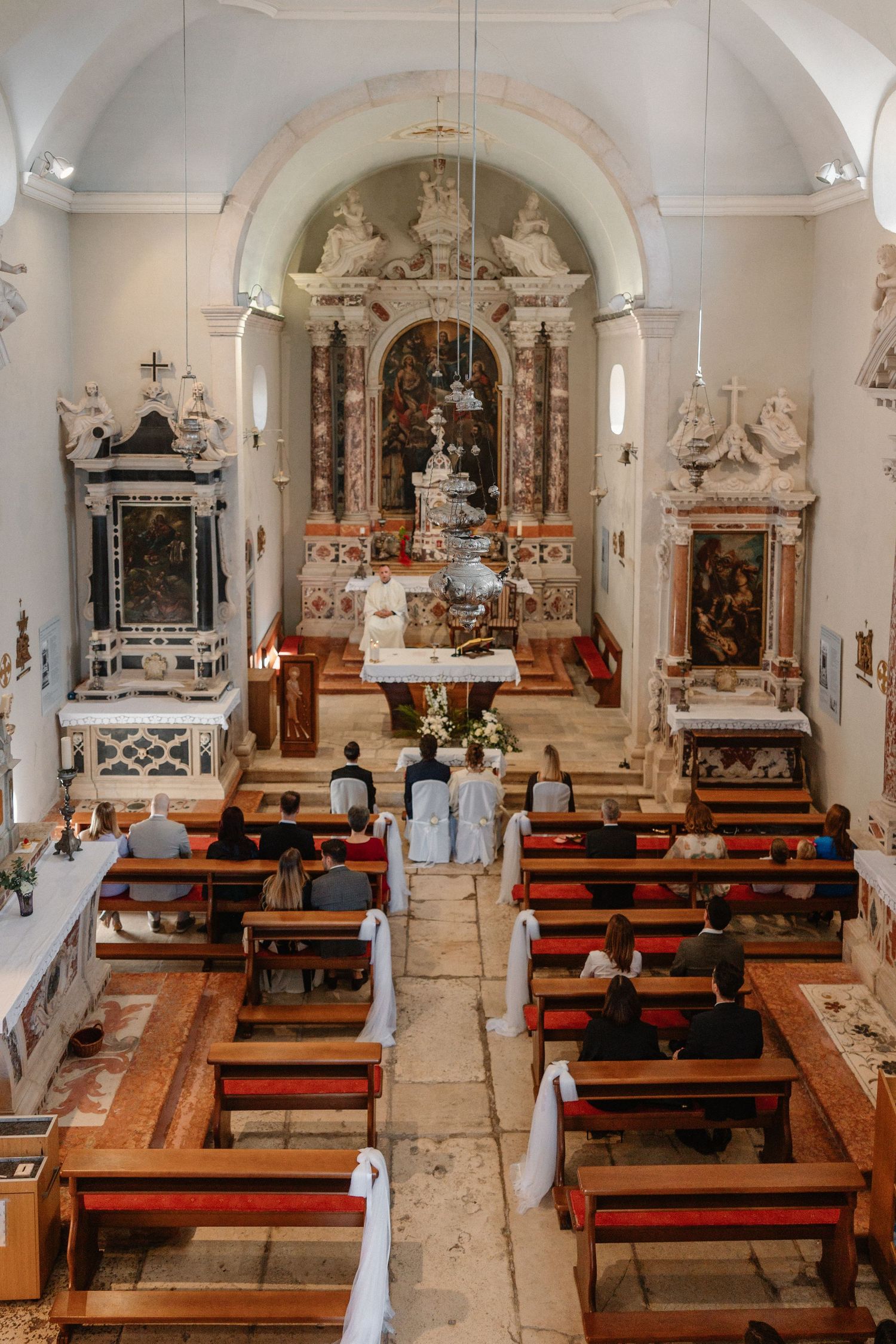 Interior of ornate church sanctuary with wooden pews and decorative altars.