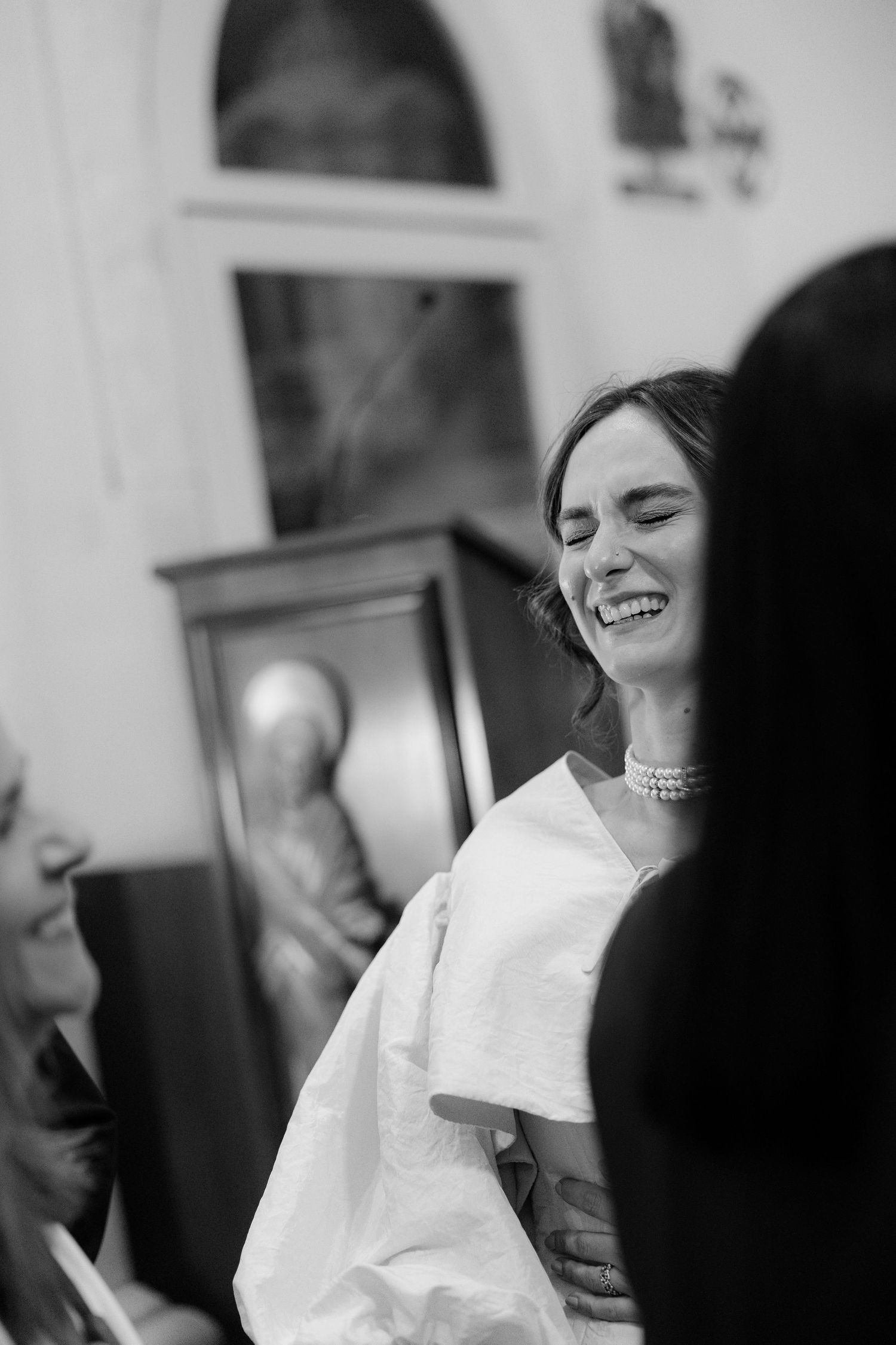 Joyful candid moments captured during wedding preparations in black and white.