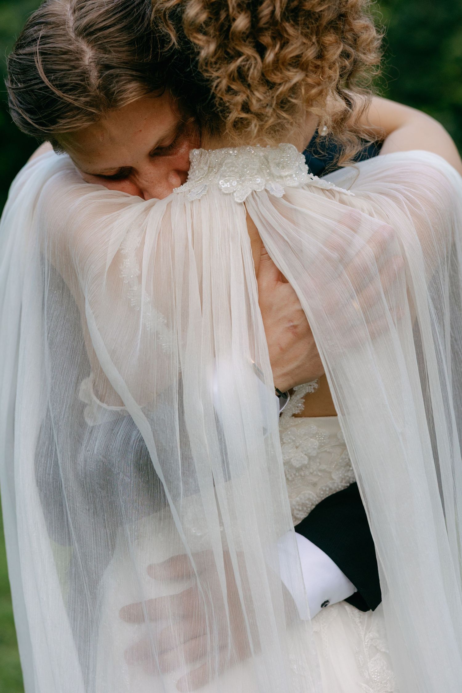 A series of romantic wedding photos showing a couple embracing through flowing white tulle veil outdoors.