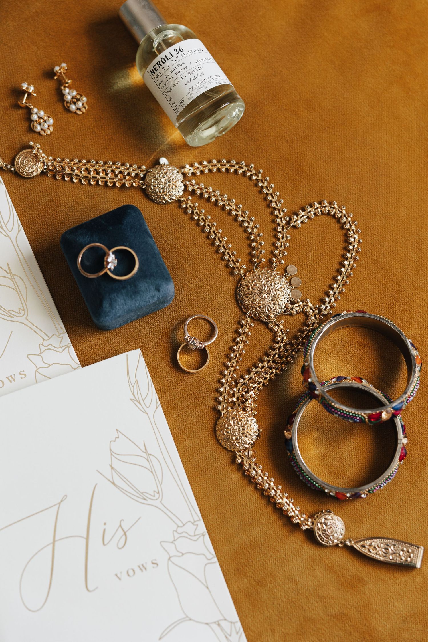Wedding rings and elegant jewelry displayed on a brown leather surface with white paper details.