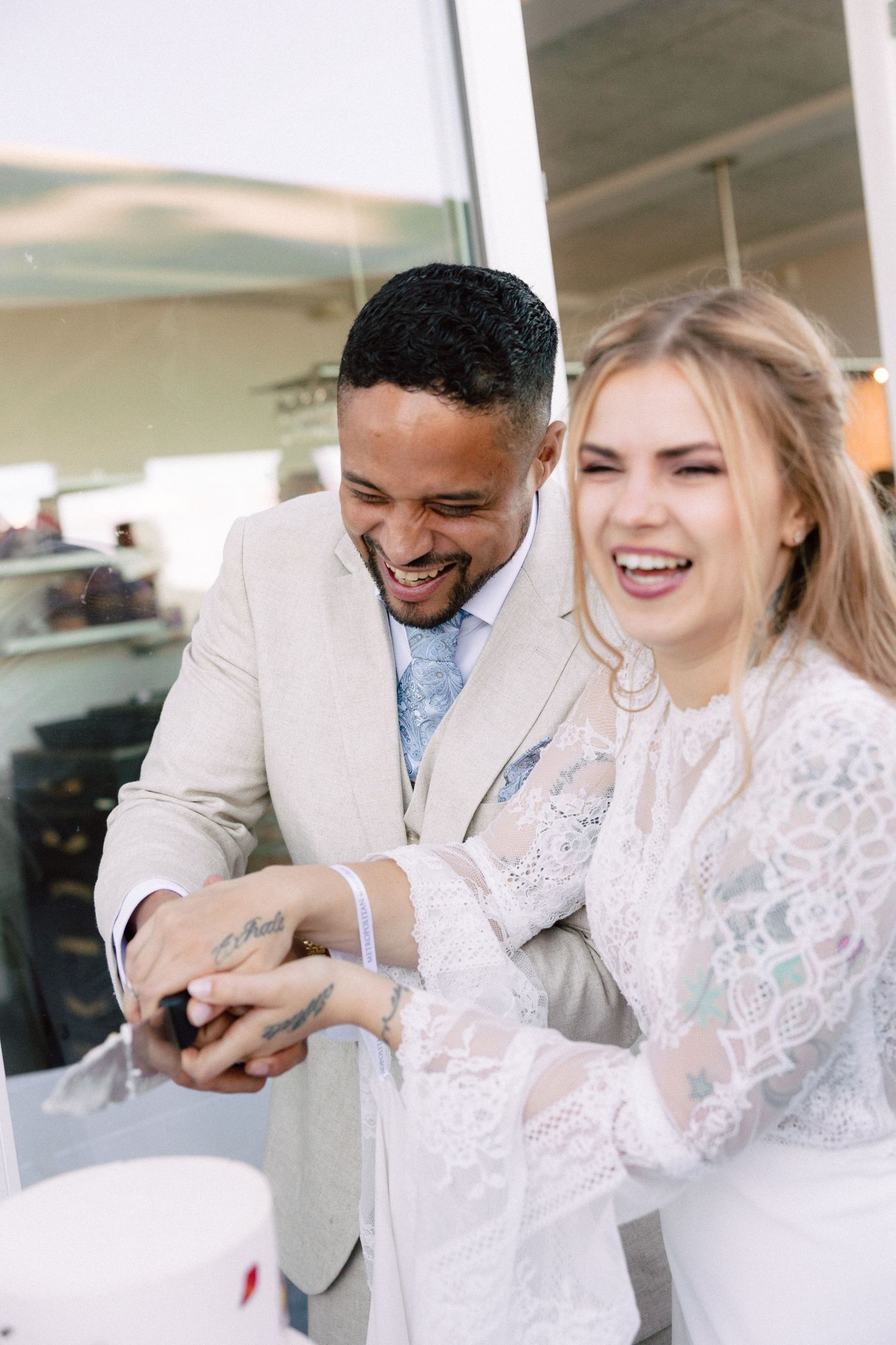 Wedding couple laughing together while seated at reception table.