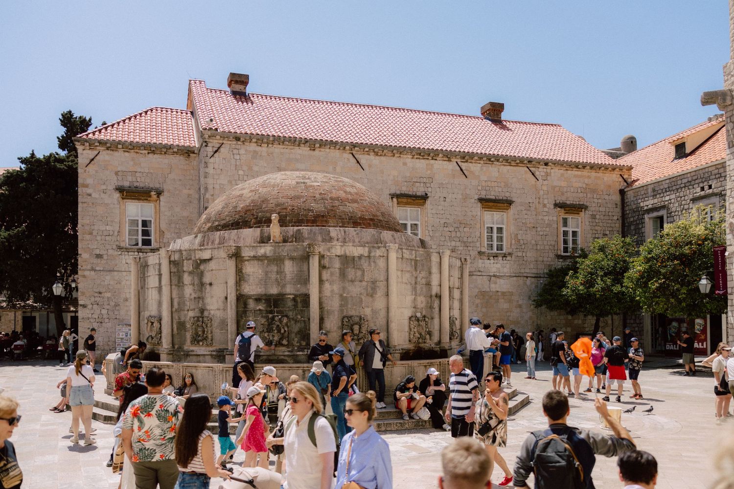 Historic stone courtyard with red-tiled roofs and gathering of wedding guests  in Dubrovnik, Croatia.