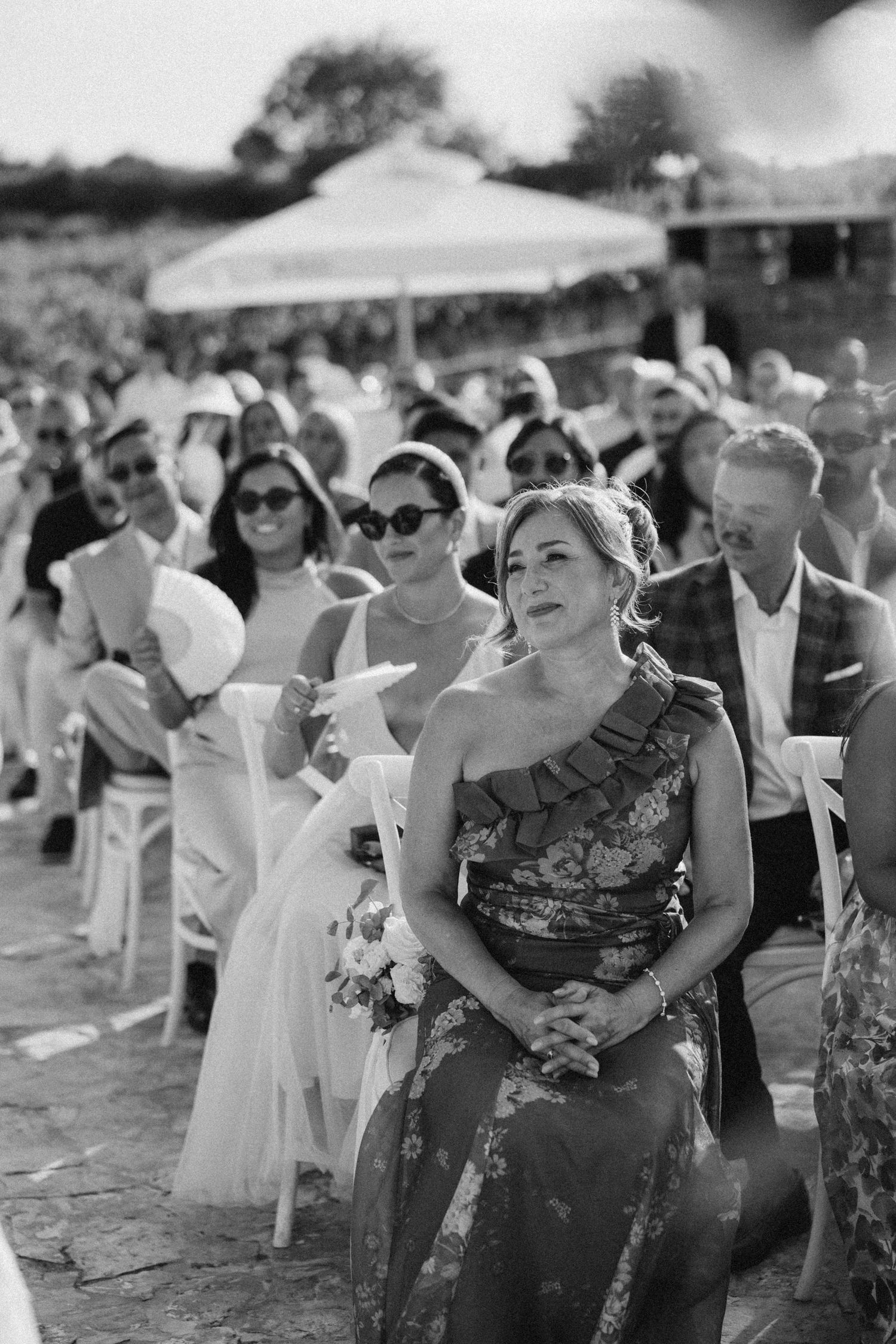 Black and white photo of wedding guests watching ceremony with emotional expressions.