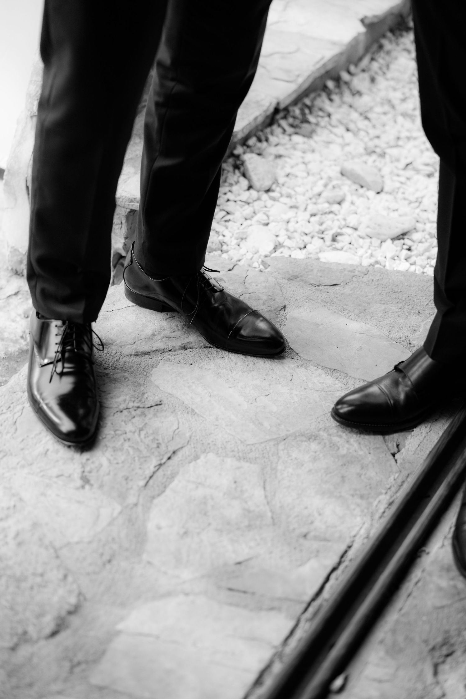 Black dress shoes and formal wear on a stone floor at a wedding.