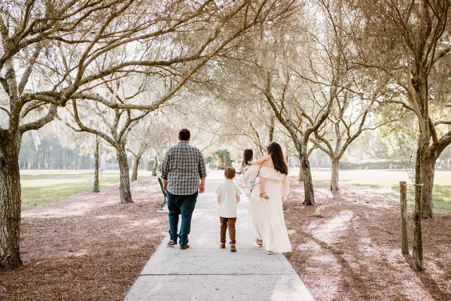 Family walking together through a scenic tree-lined path.