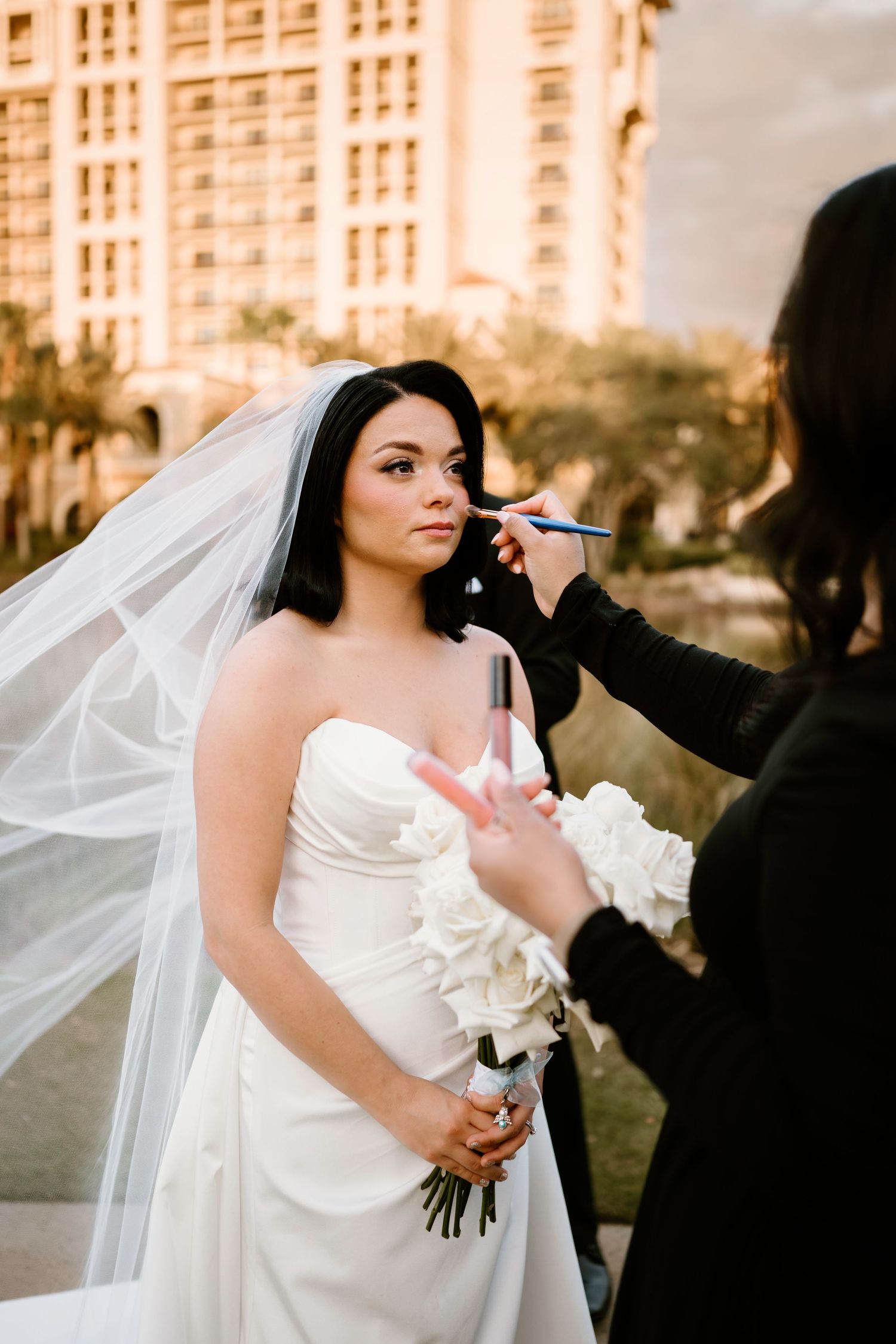 Final touches being applied during wedding preparation with a resort building in the background.