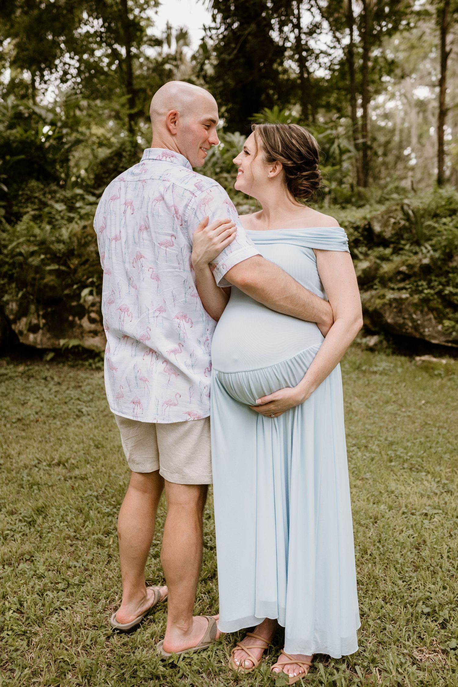 Couple in light blue dress and patterned shirt sharing an intimate moment in a garden setting.