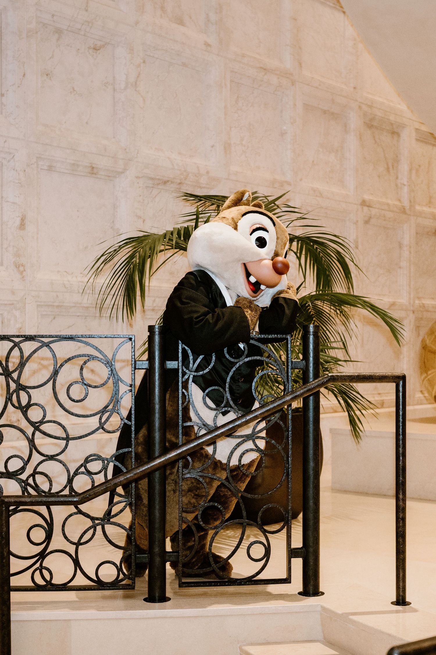 Disney character mascots dance along decorative railing at wedding venue.