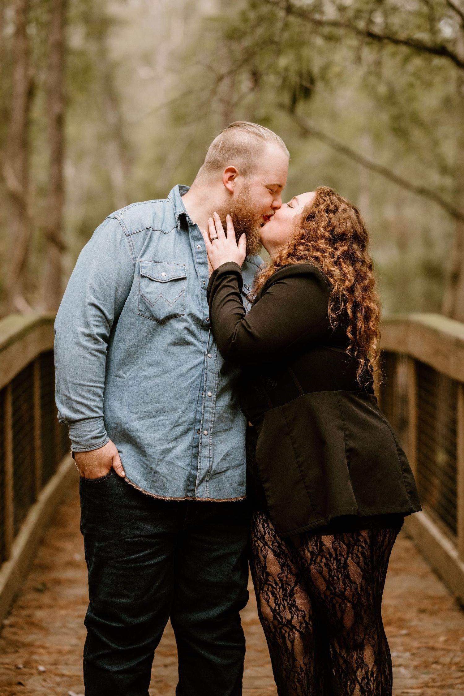 A romantic couple shares tender moments on a wooden bridge in a natural setting.