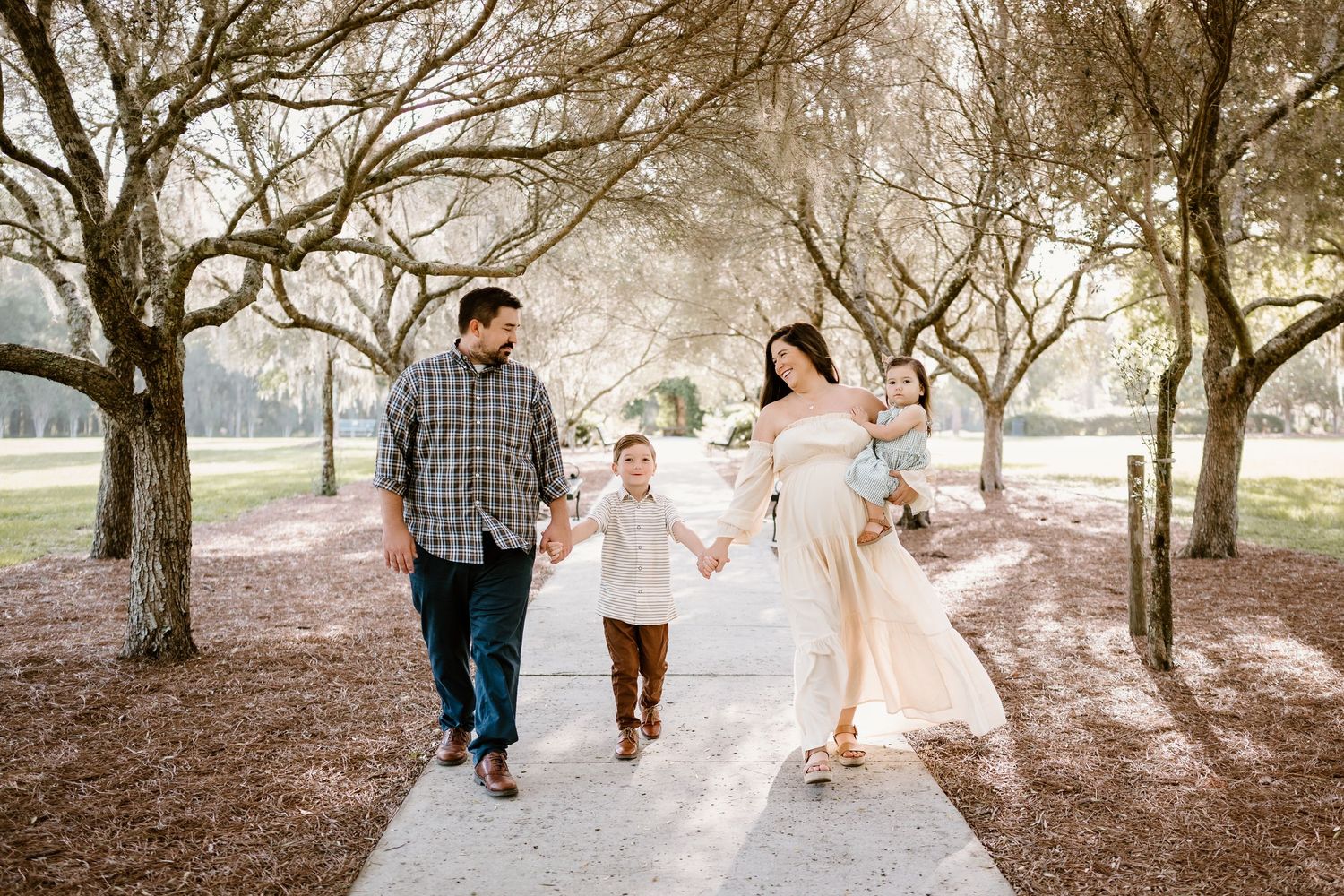A family walks together under blooming trees on a scenic path.