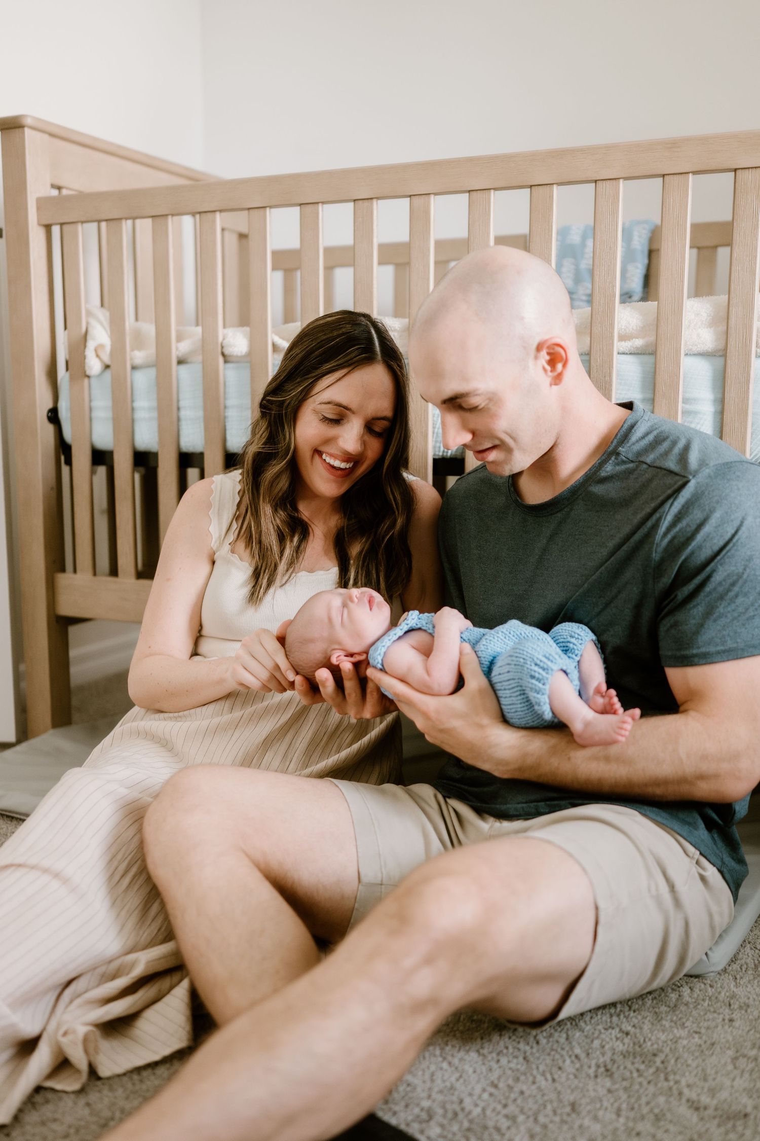 Family lying on carpet sharing joyful moments with their newborn baby.