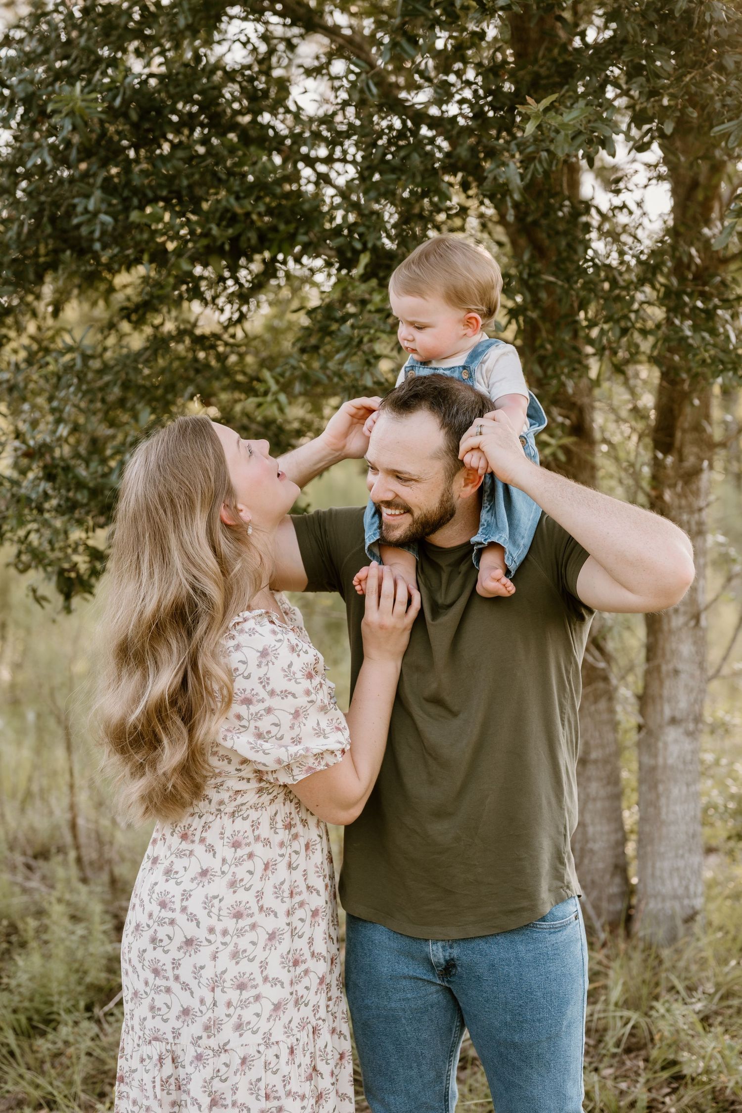 A couple and their baby share playful moments during an outdoor photo session.