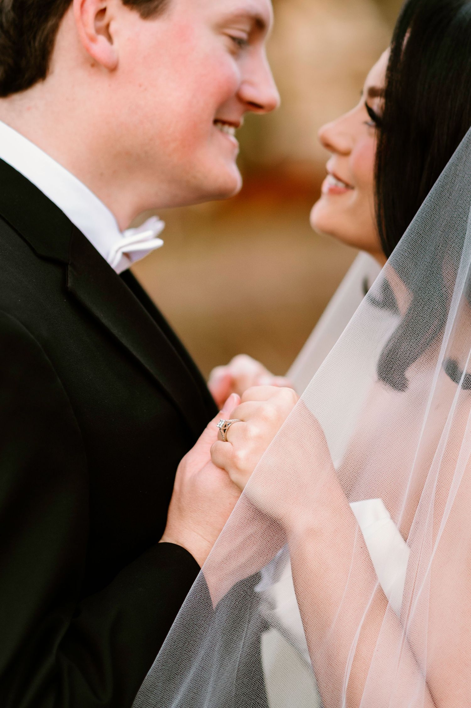 Close-up wedding portrait with delicate veil creating intimate romantic moment.