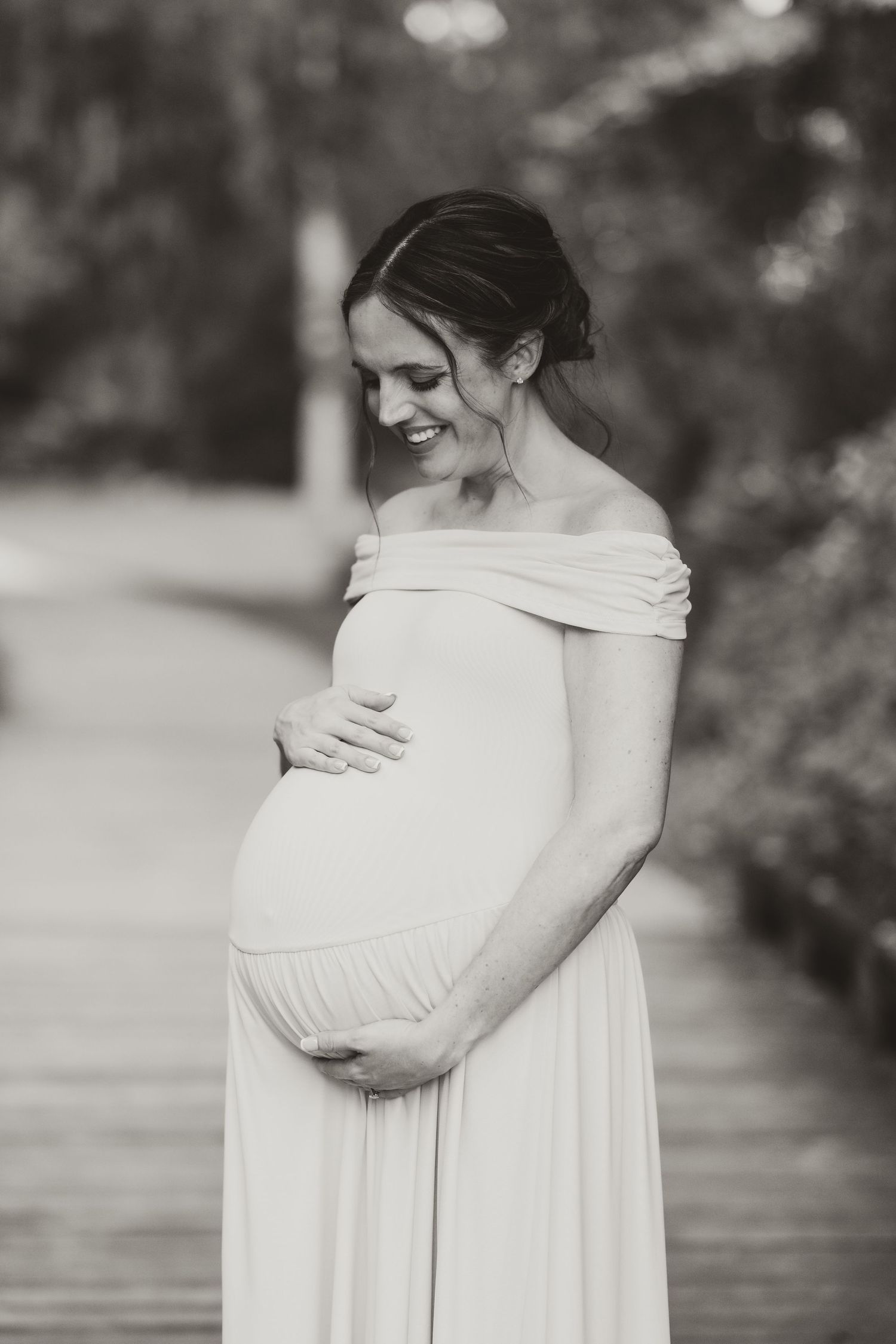 Black and white series showing a pregnant woman cradling her baby bump in a white dress.