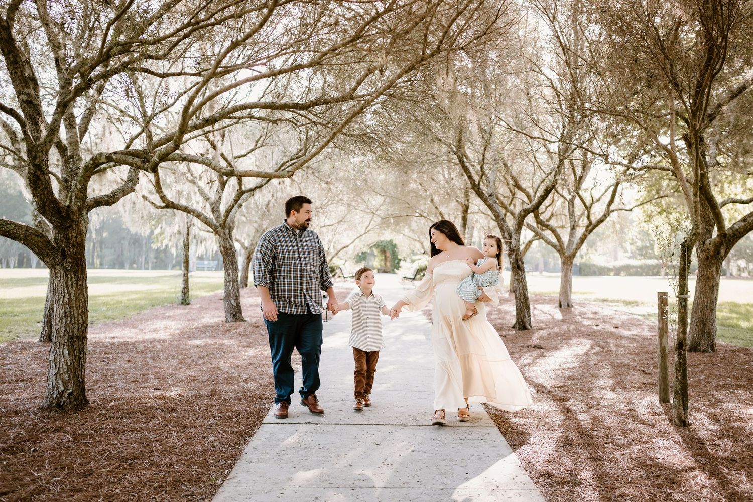 Family enjoying a stroll together on a concrete path surrounded by trees.