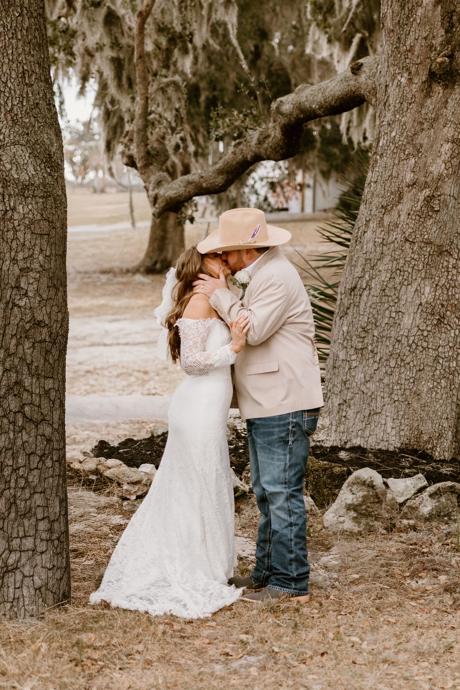 A romantic outdoor photo session under oak trees showing tender moments between a couple in wedding attire.