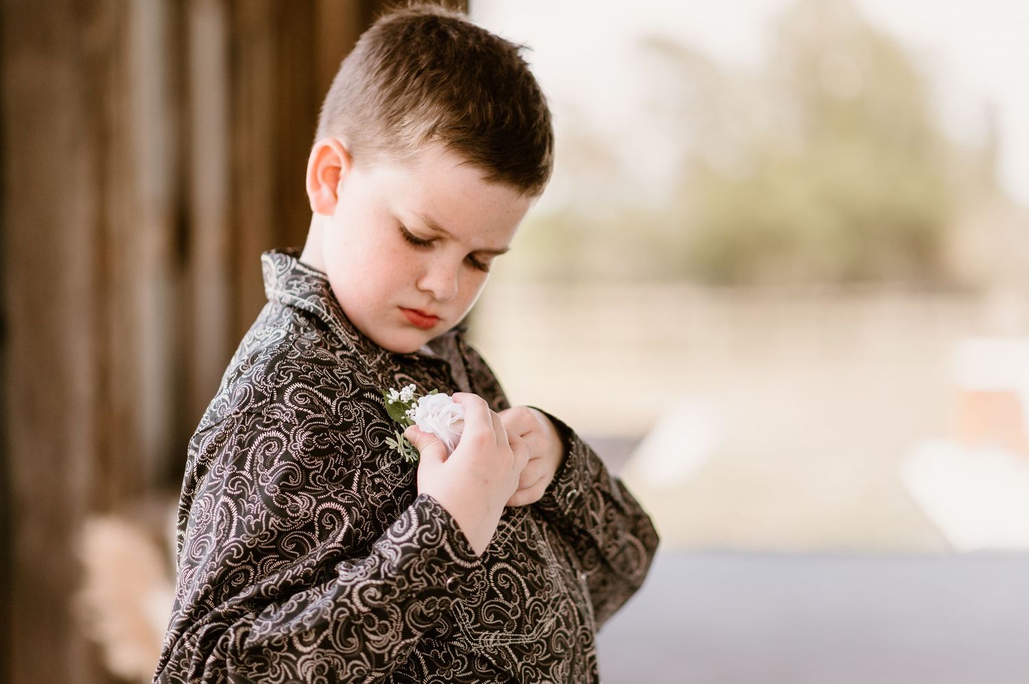 Young child in a brown sweater looking down thoughtfully.