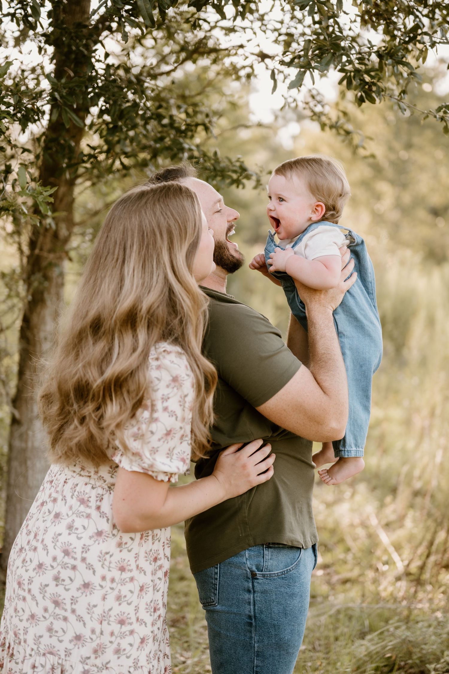 A family shares tender moments together against a backdrop of trees during a photo session.