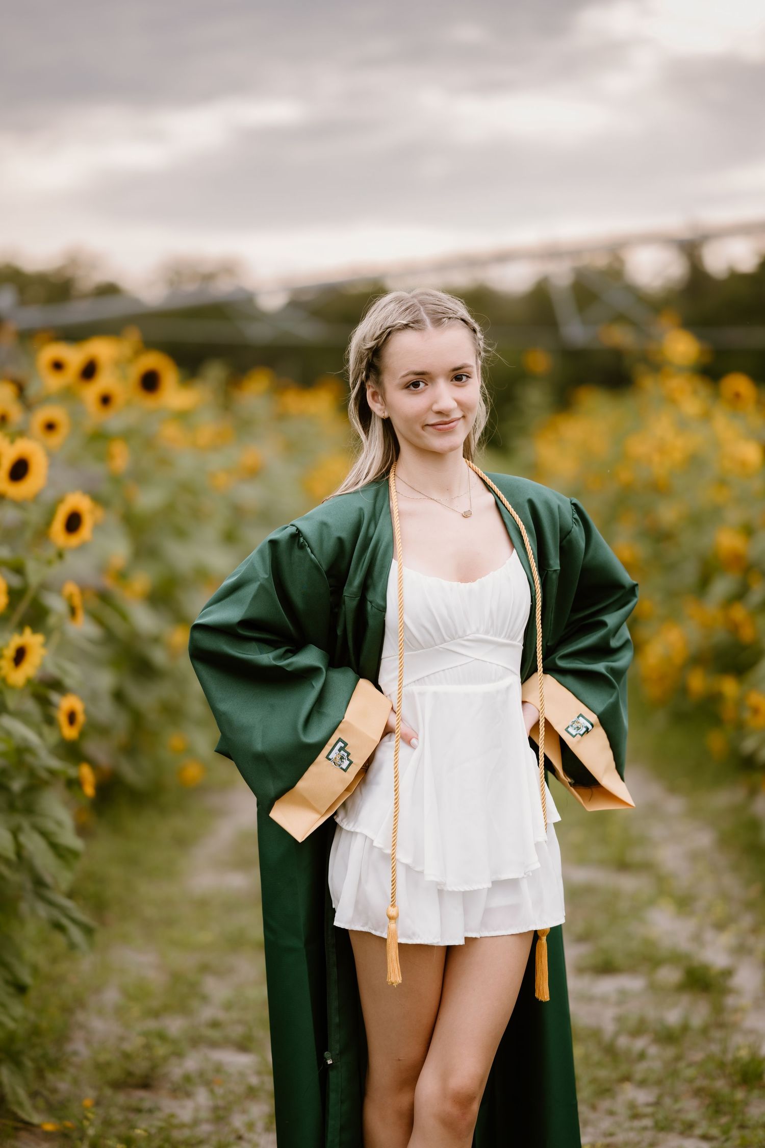 Sunflower field backdrop with green coat and white outfit in summer setting.