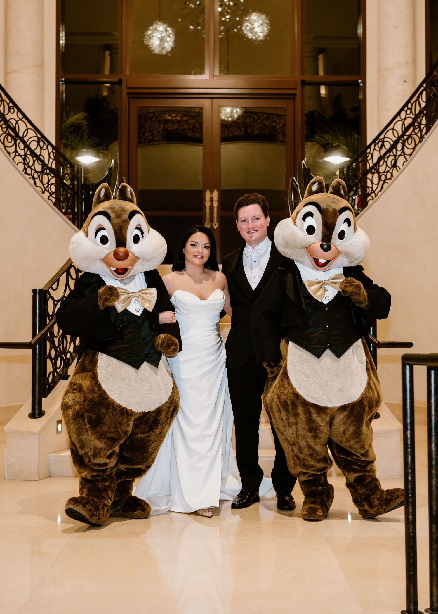 Disney chipmunk characters pose with wedding couple on grand staircase.