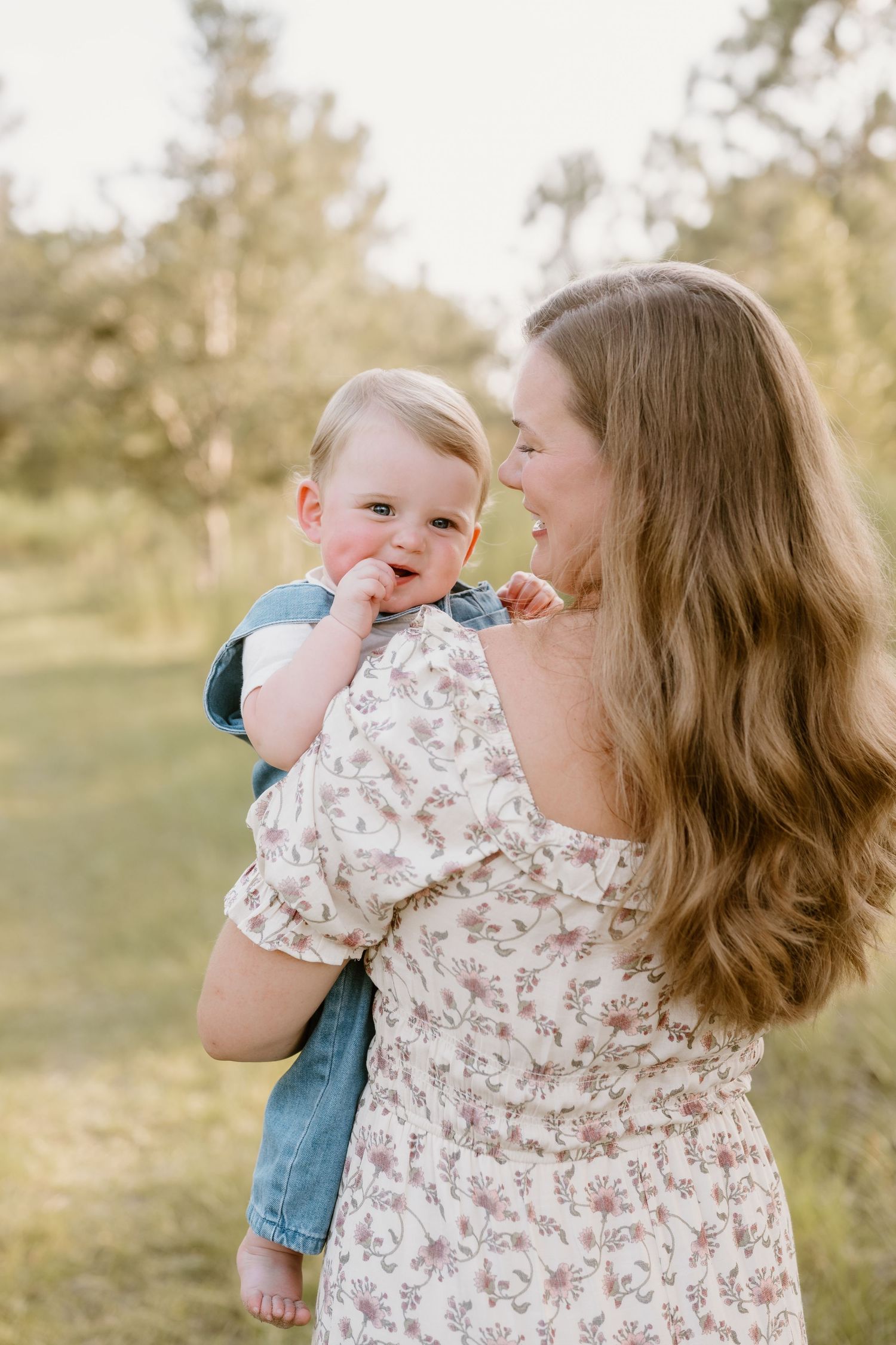 Parent and baby sharing affectionate moment outdoors in soft lighting.