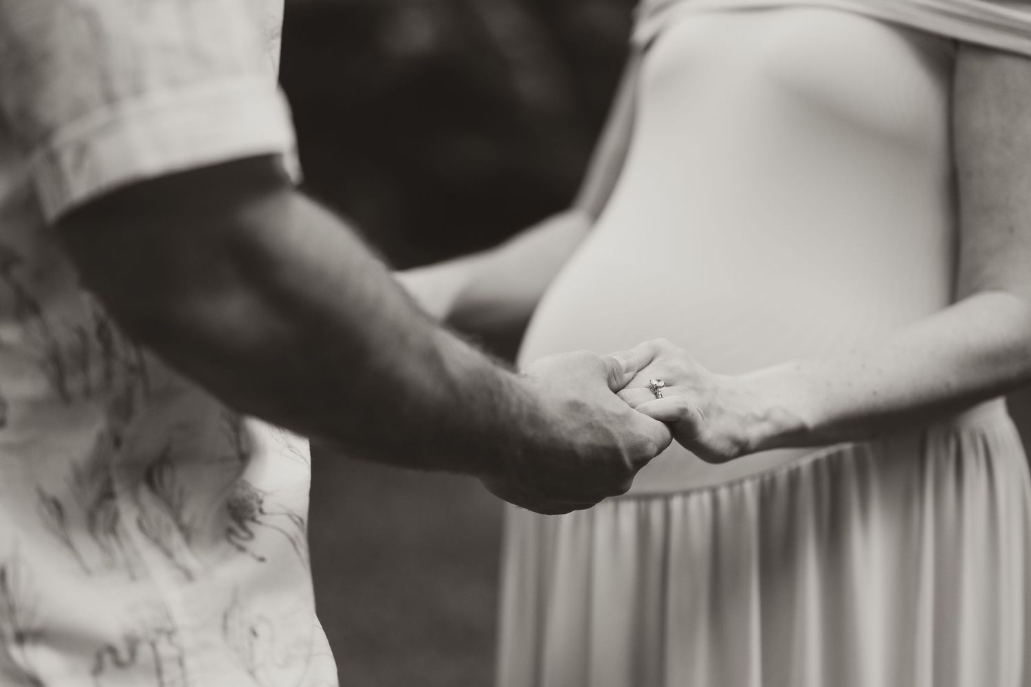 Close-up details of hands holding each other in formal attire.