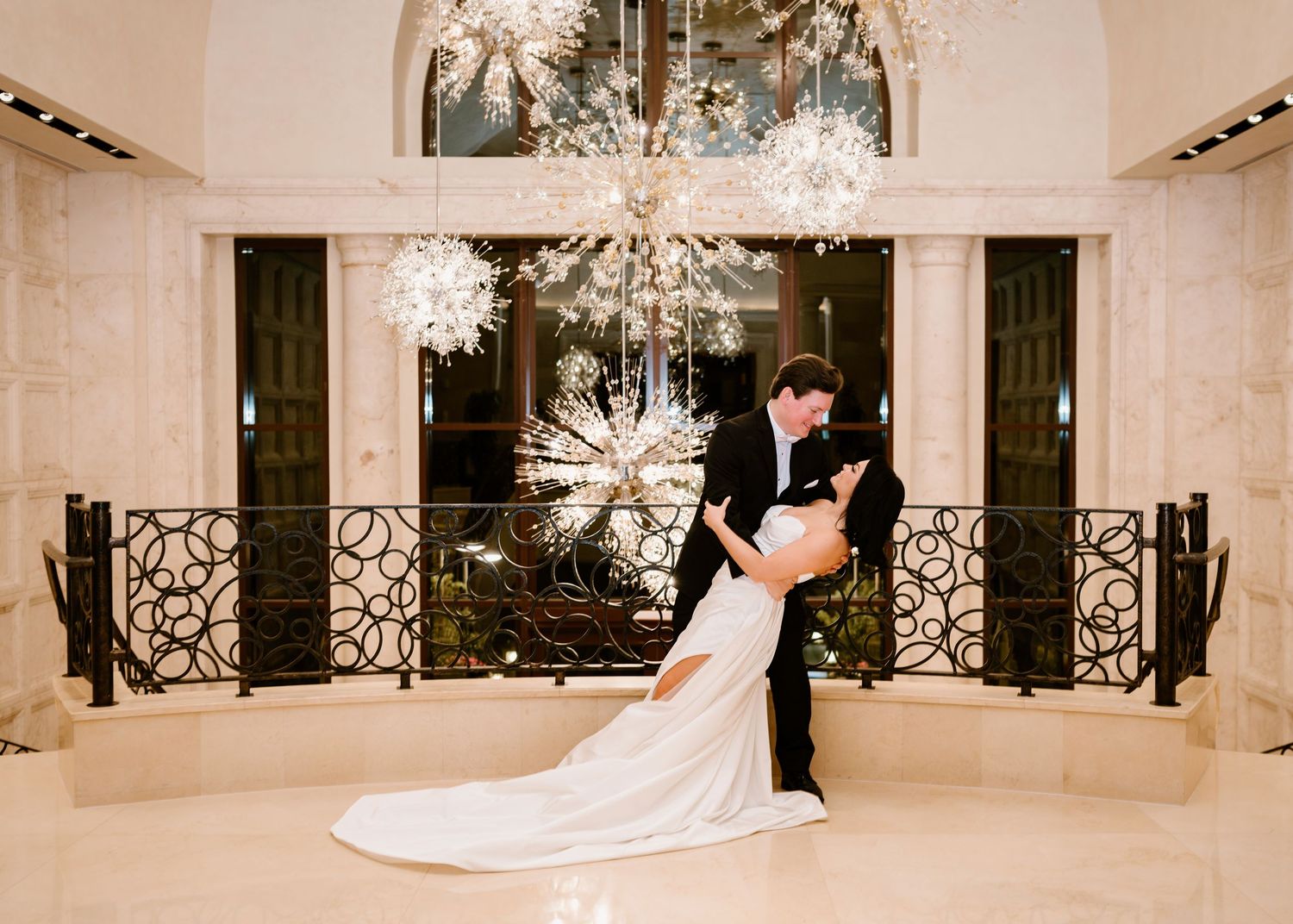Grand marble staircase in wedding venue decorated with crystal chandeliers.