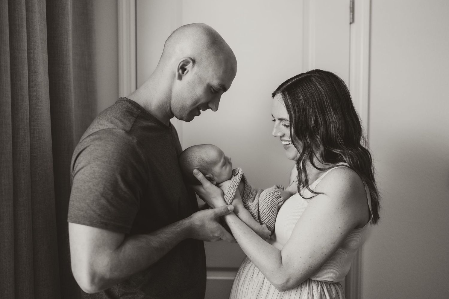 Intimate black and white photos of parents bonding with their newborn baby indoors.