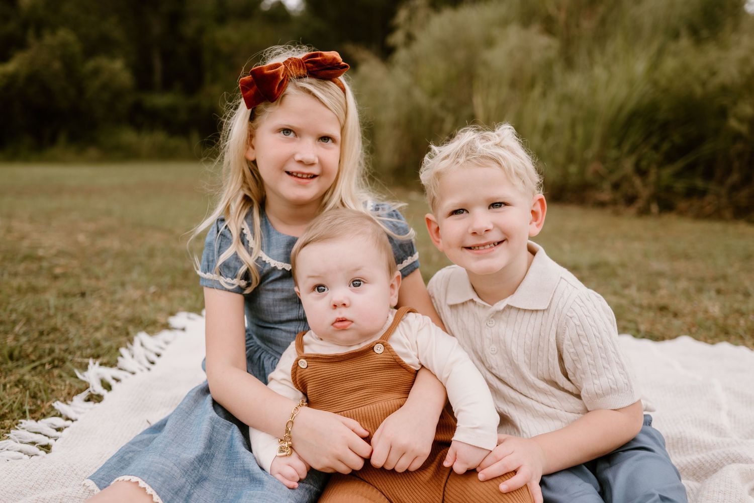 Candid family portrait with children playing and laughing together outdoors.