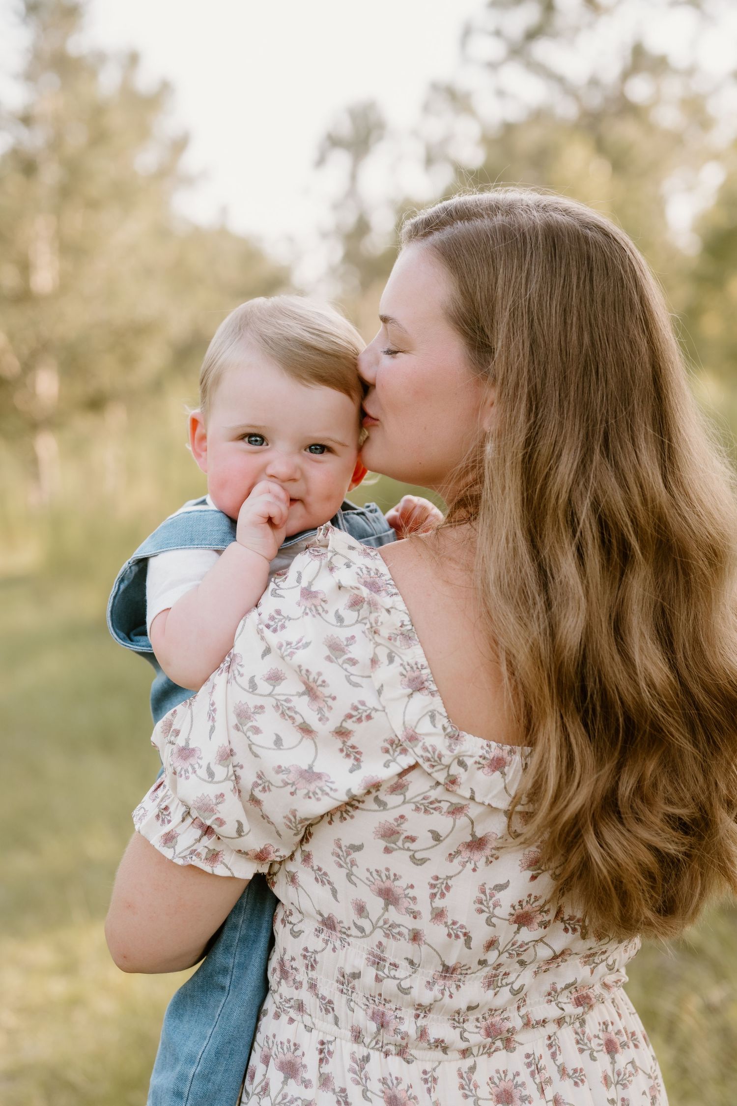 A tender moment between parent and baby in a floral dress against a soft natural background.