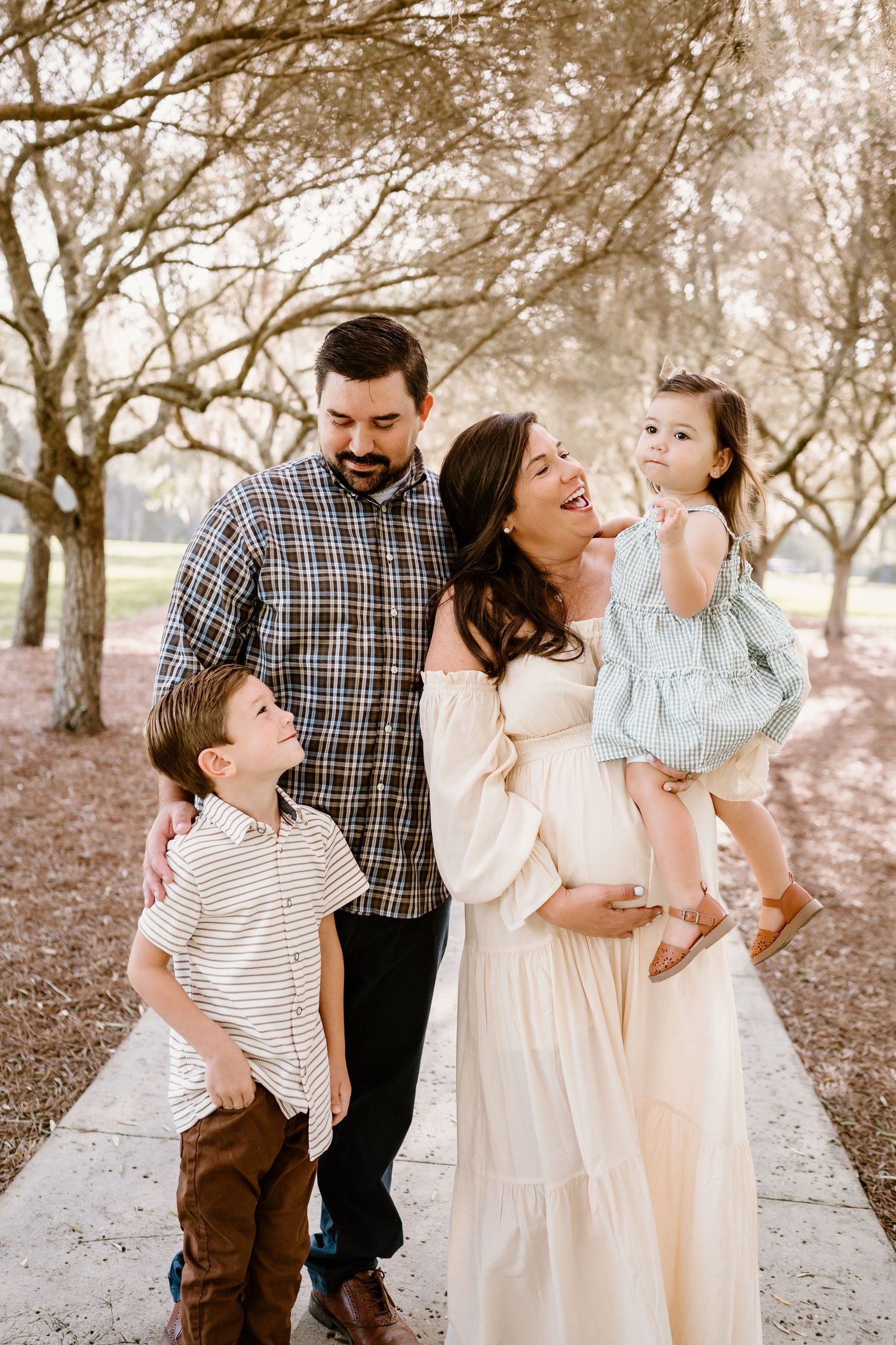 Family portrait in a dreamy park setting with blooming trees creating a romantic atmosphere.