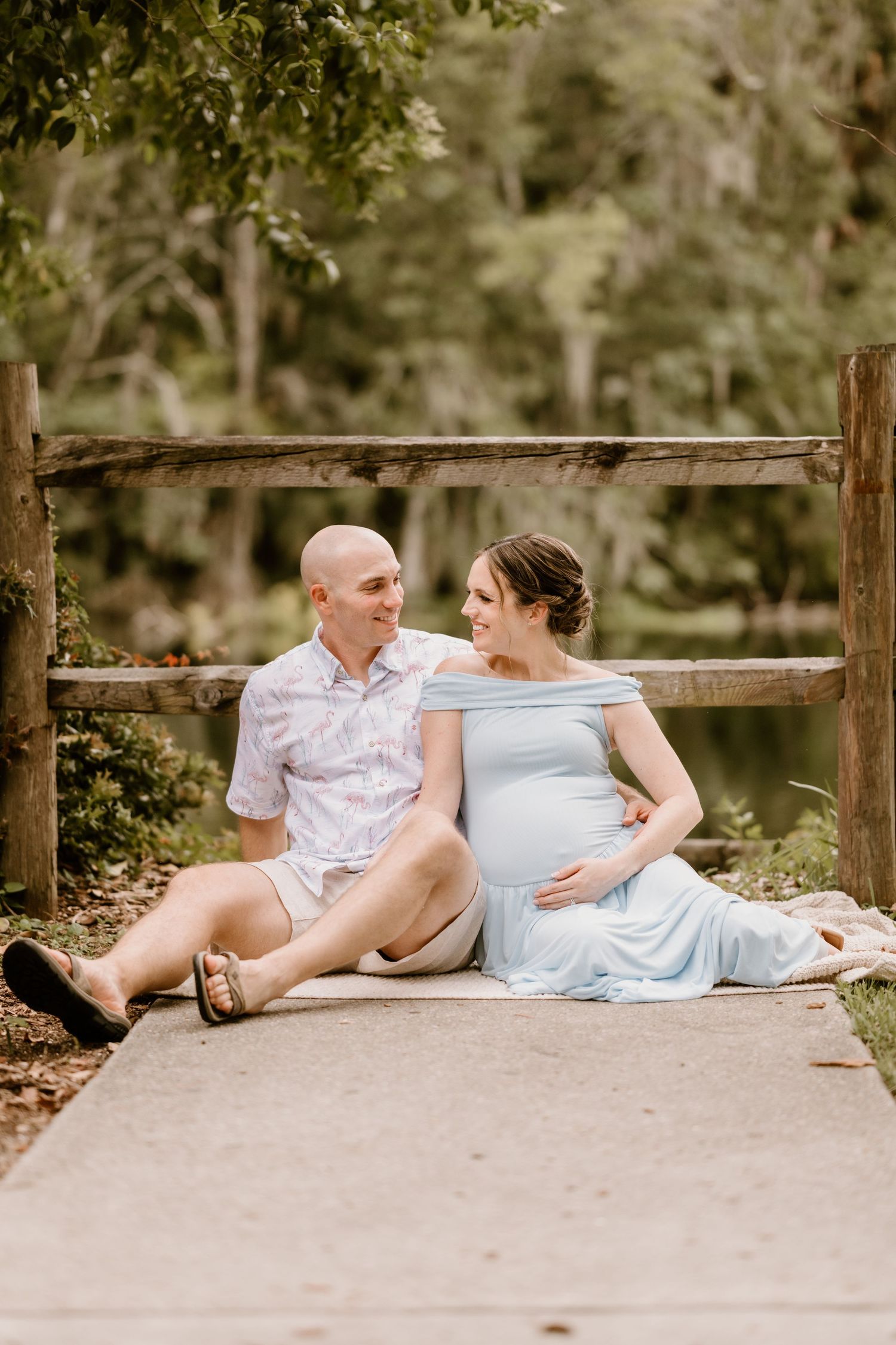 Couple in casual attire relaxing together on wooden deck surrounded by greenery.