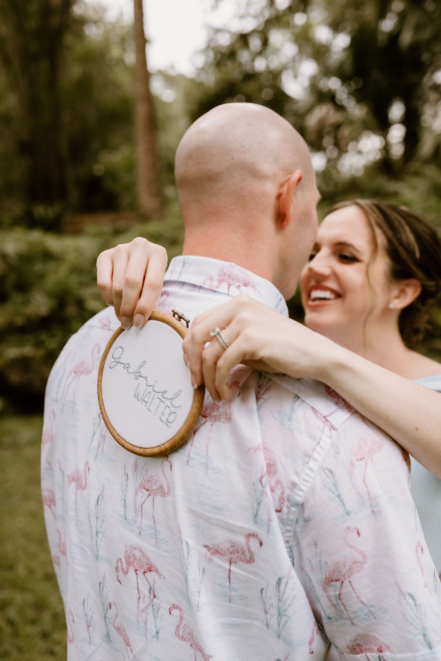 Couple sharing intimate moment outdoors while showing embroidery hoop artwork.