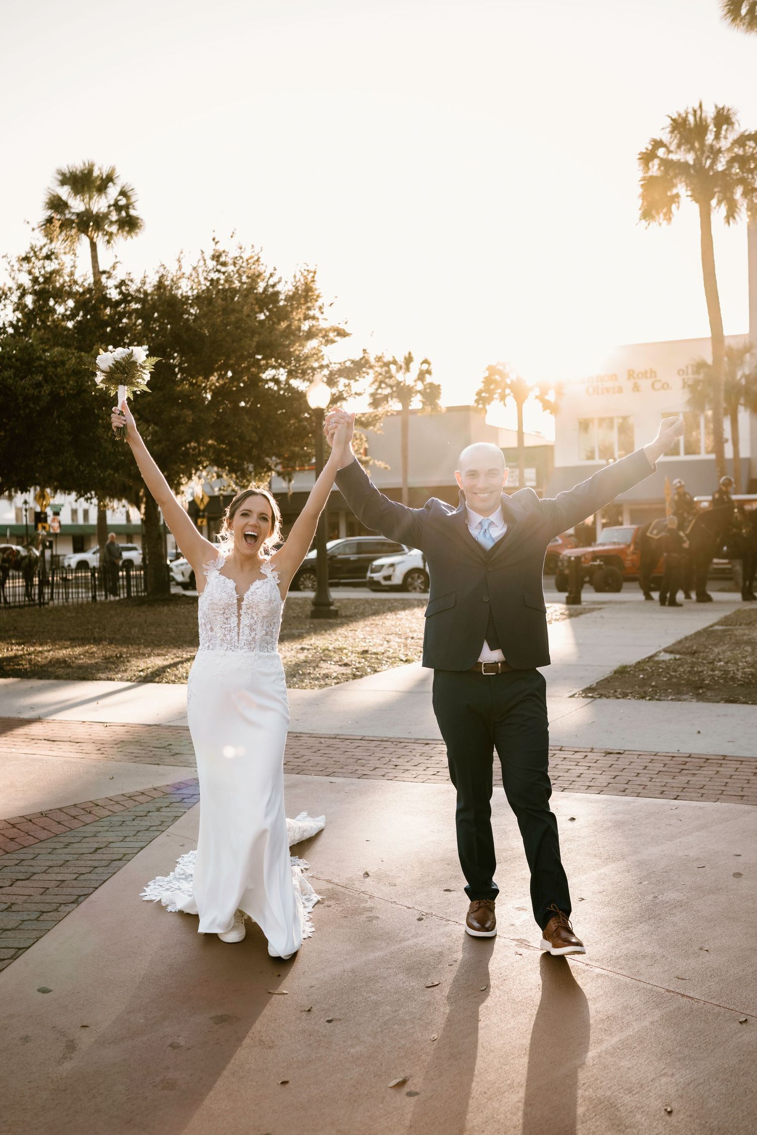 Joyful wedding couple dancing and celebrating at sunset on a brick paved walkway.