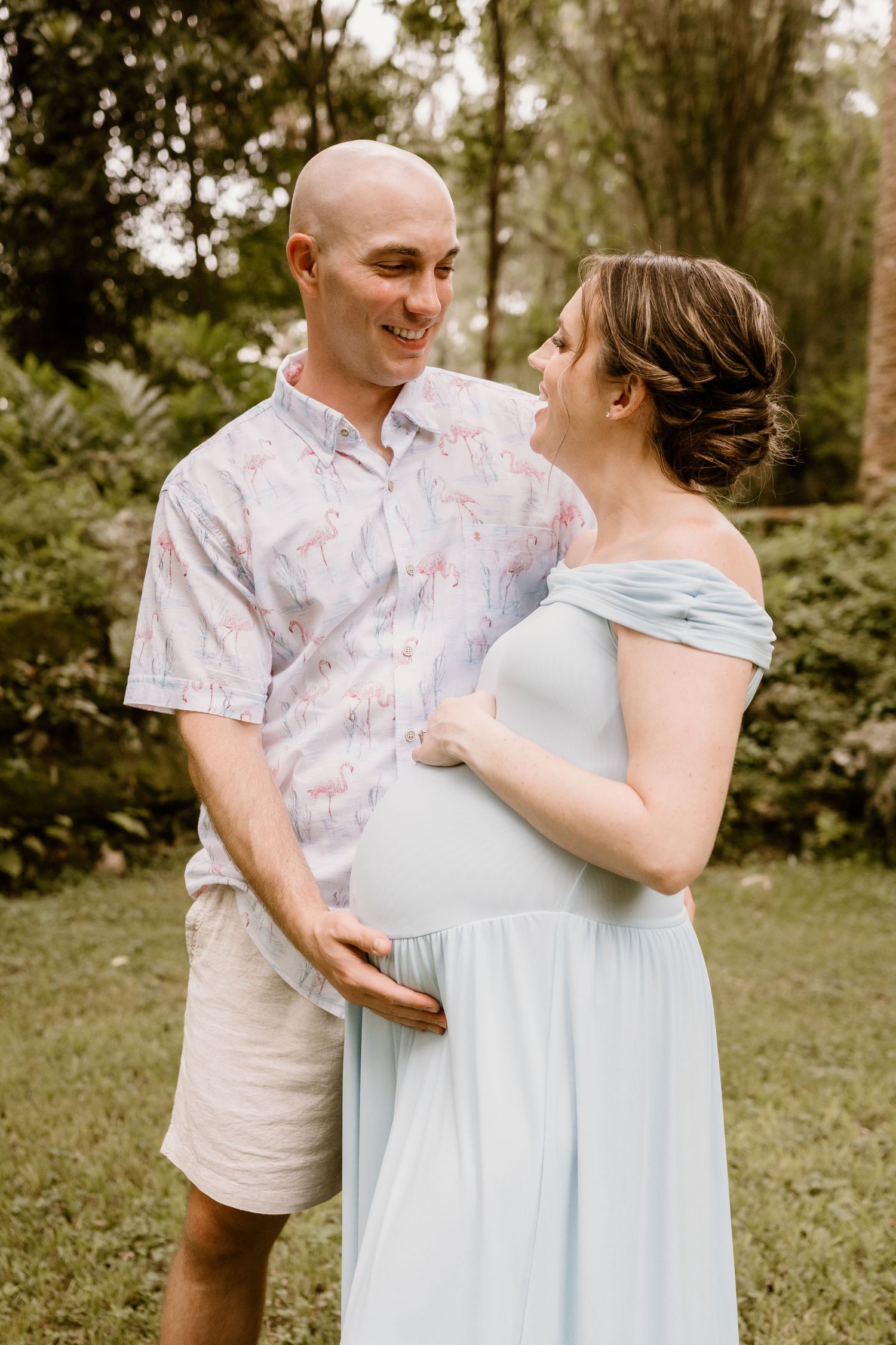 Couple in light blue dress and floral shirt embracing outdoors during a photo session.