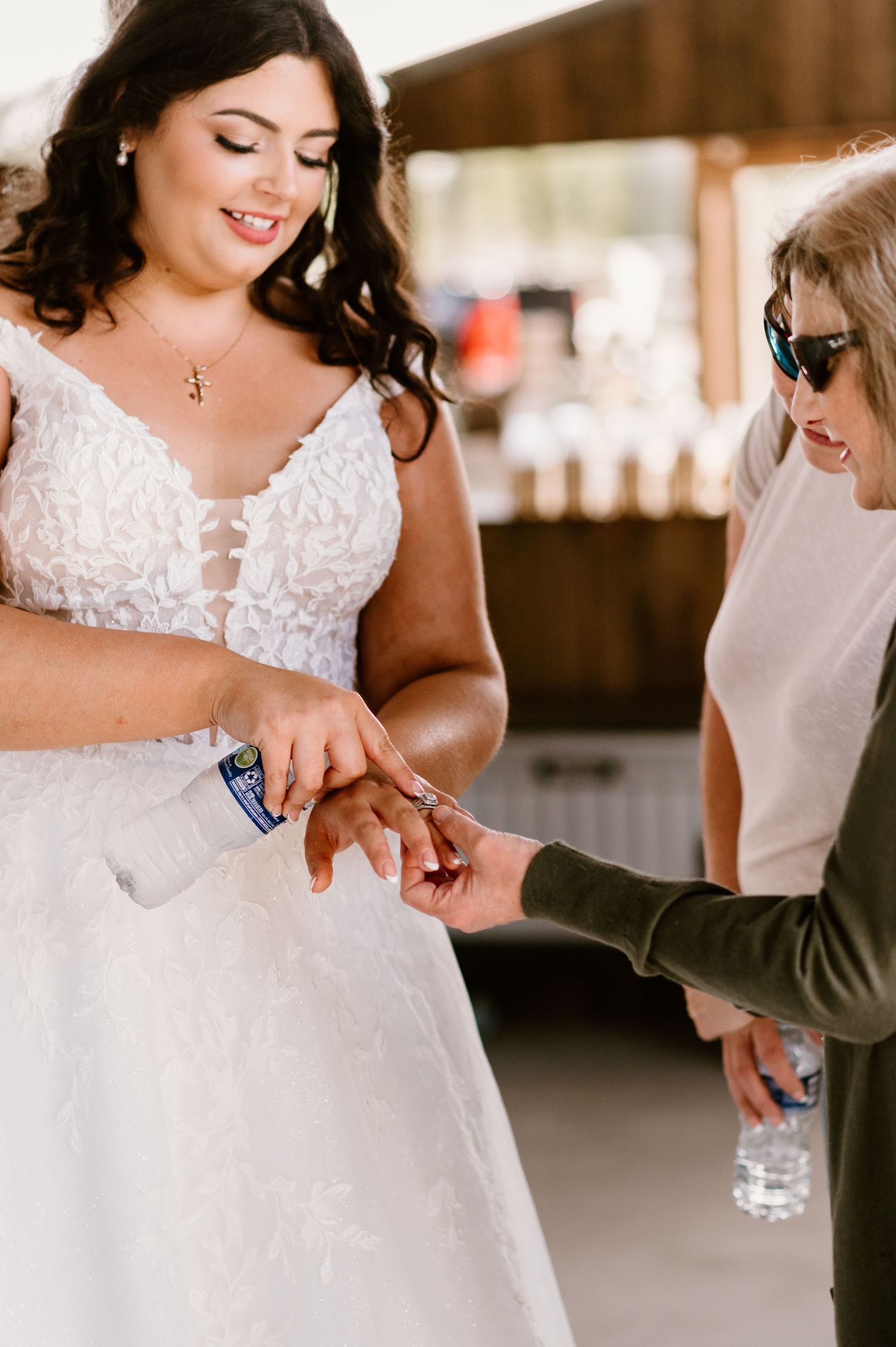 Close-up of bride in lace dress during wedding preparation moment.