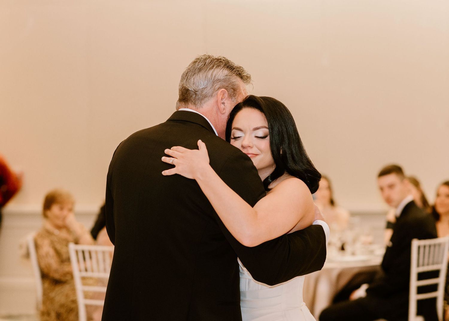 Wedding guests dancing and celebrating in a cream-colored reception hall.