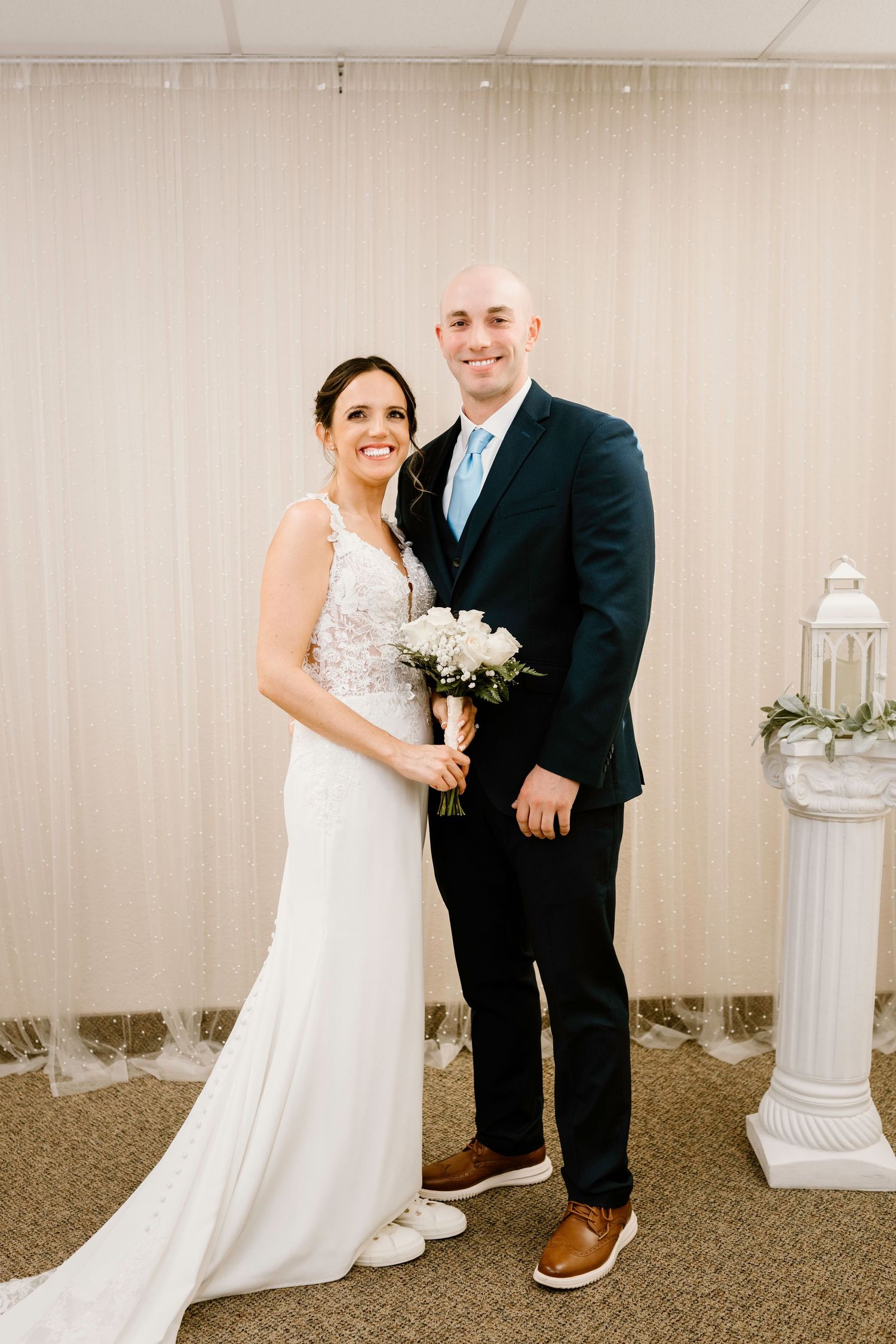 Wedding portraits taken indoors with decorative white columns and neutral backdrop.