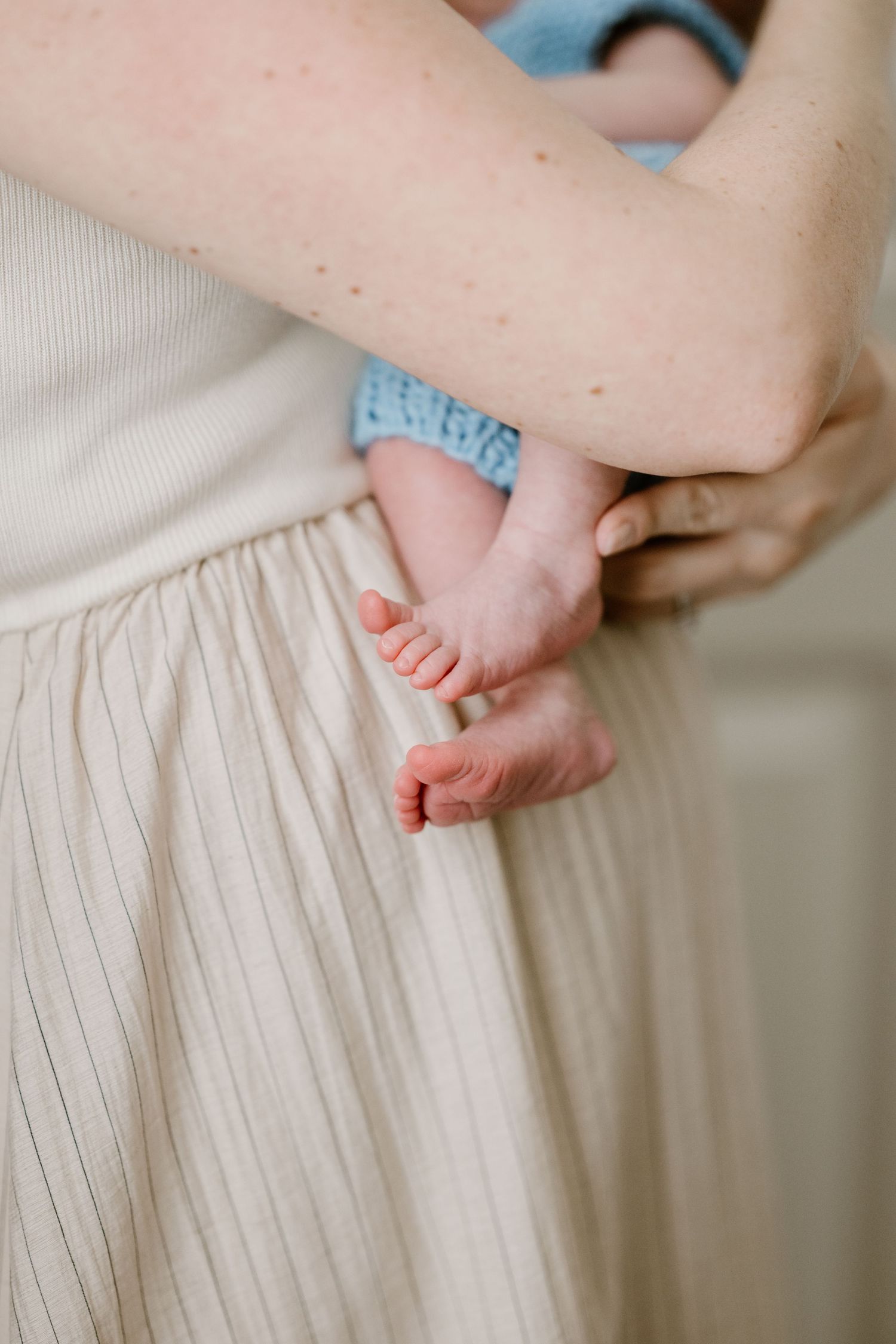 Close-up detail shots of tiny baby feet against soft striped fabric.