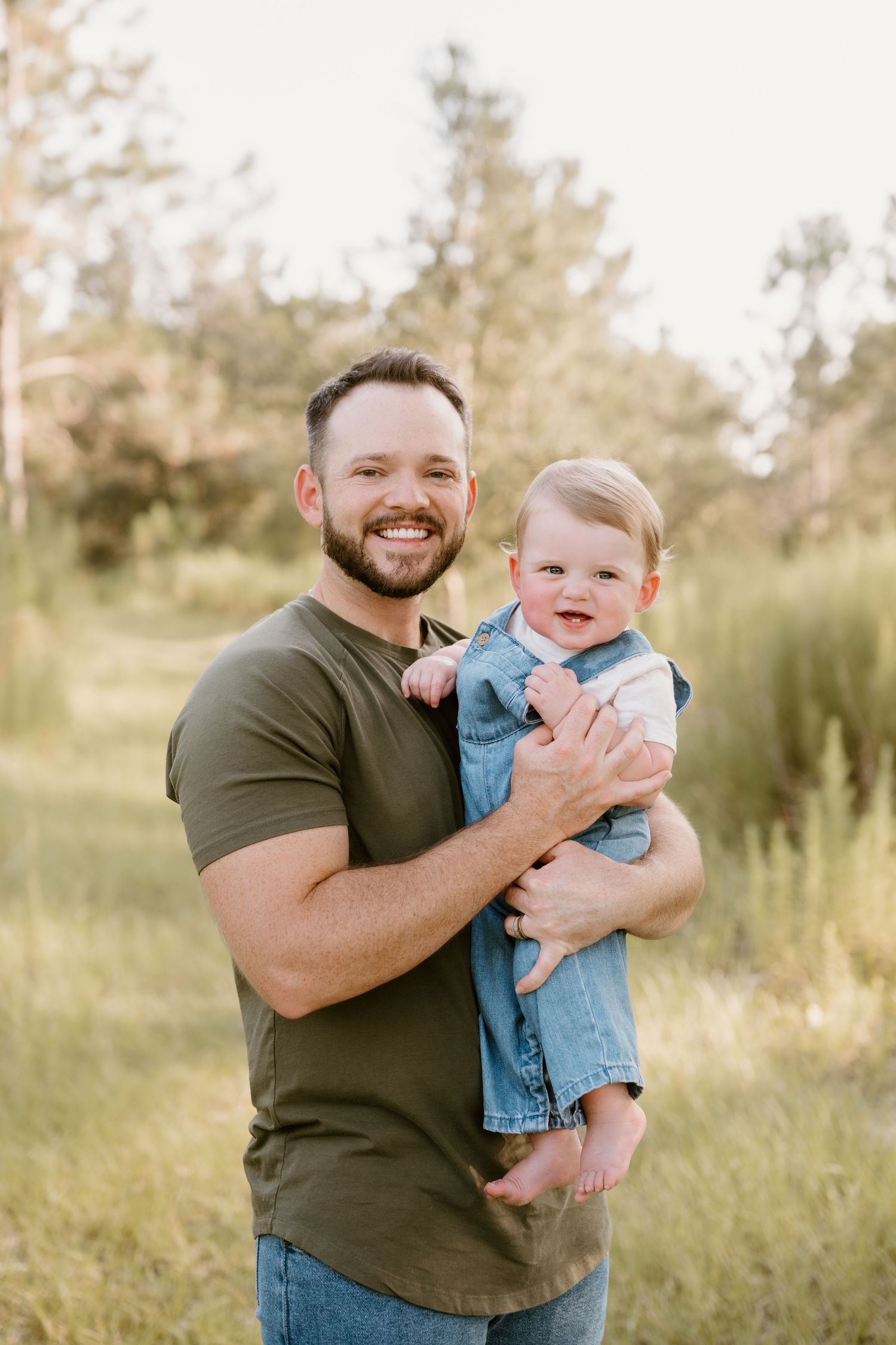 Joyful interaction between parent and laughing baby outdoors in a natural setting.