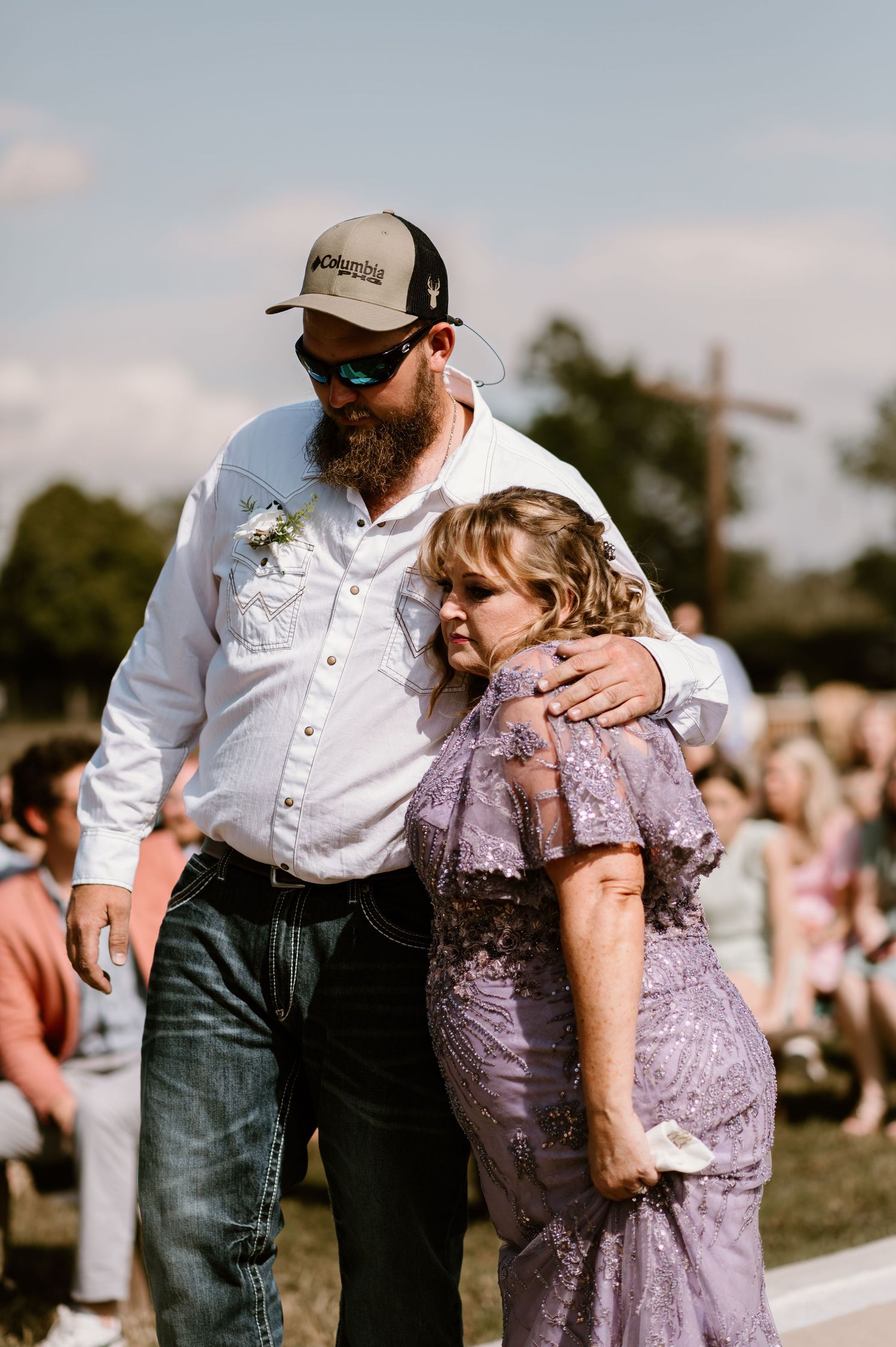 Emotional moment between wedding guests during outdoor ceremony.
