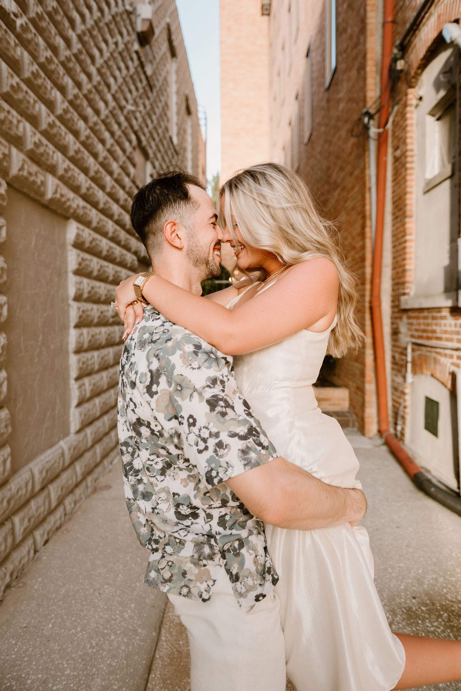 Romantic couple dancing and embracing in a rustic brick passageway.
