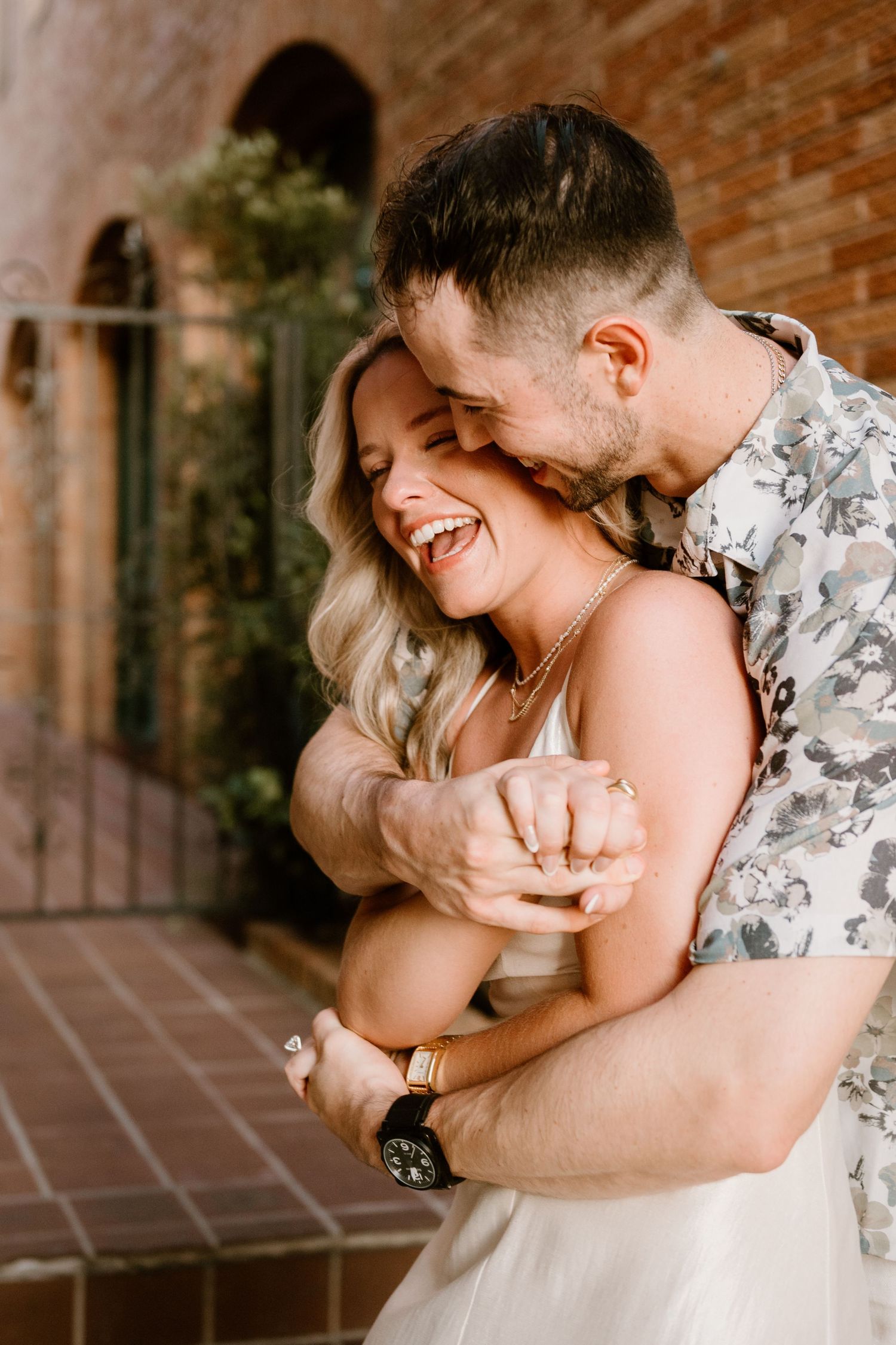Joyful couple sharing intimate moments and laughter in an outdoor walkway.