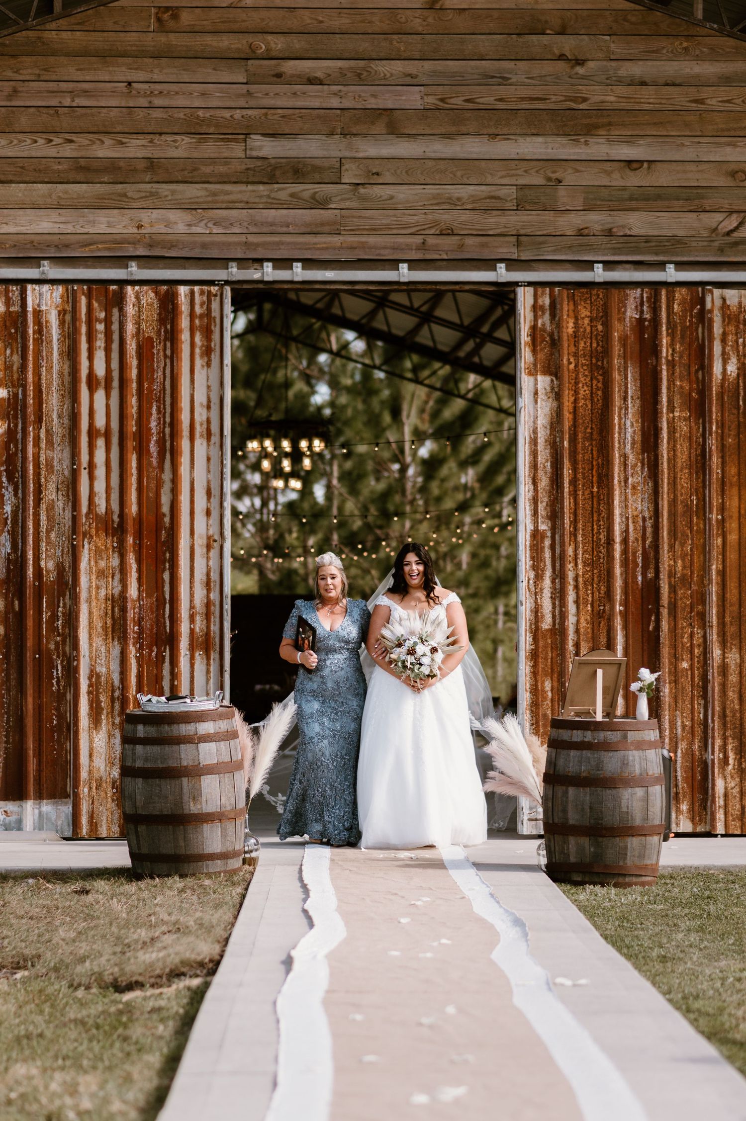 Wedding ceremony setup with wooden barrels and rustic barn backdrop.