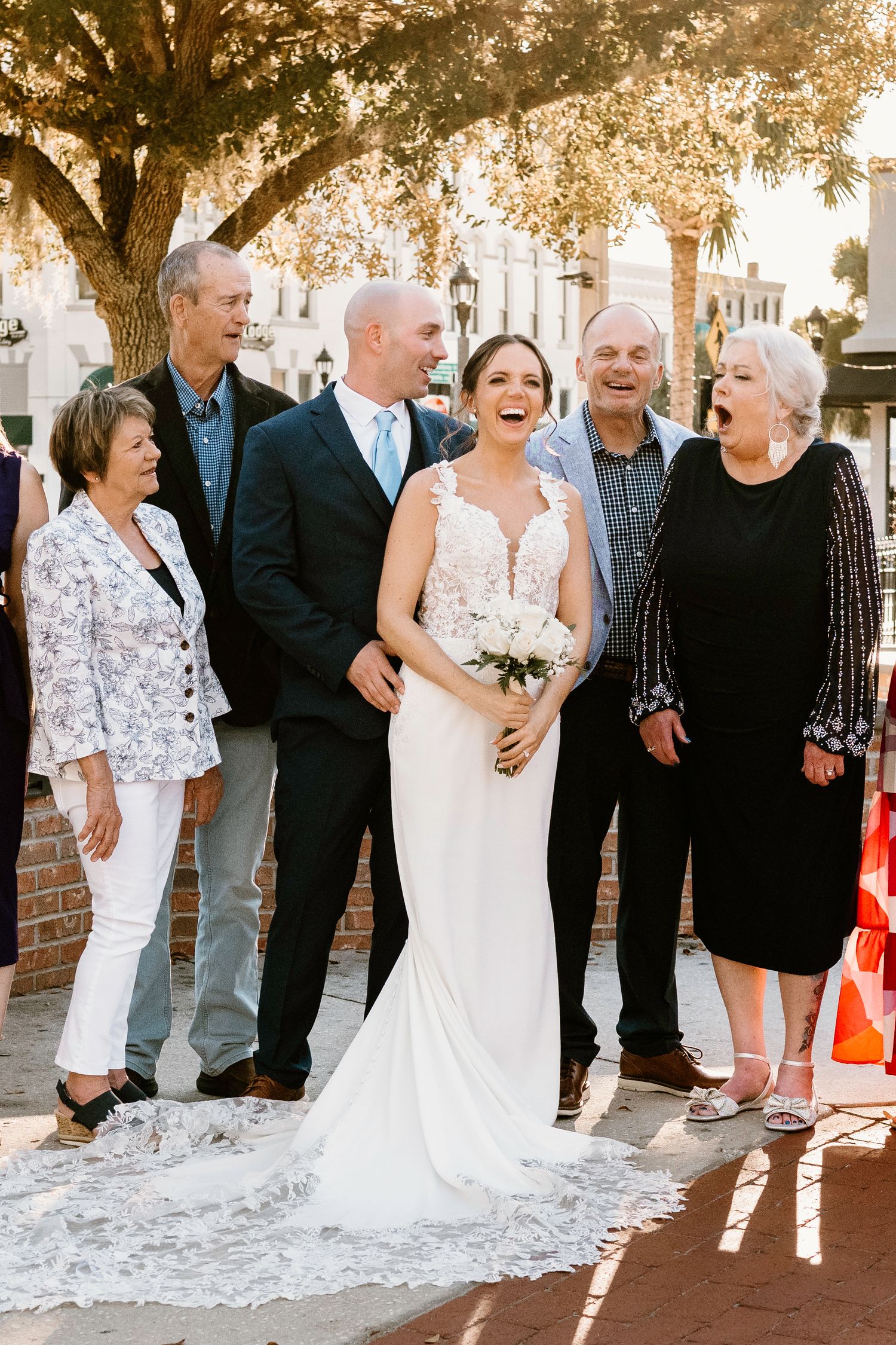 Wedding group photos taken outdoors with beautiful sunset lighting and brick architecture.