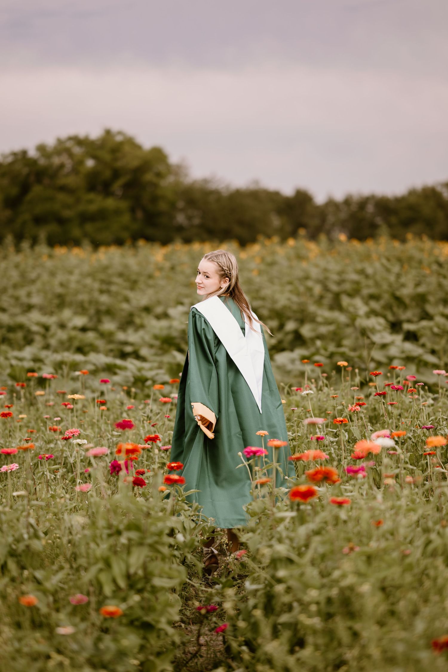 A dreamy portrait in a field of red poppies wearing a green graduation gown.