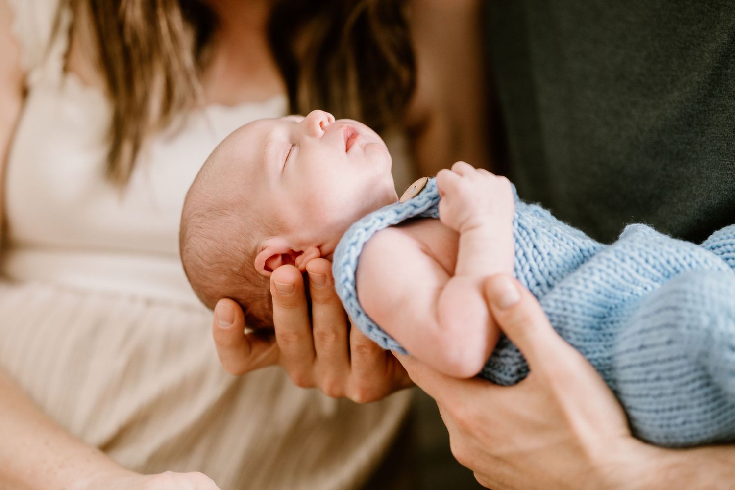 Intimate portrait of a tiny baby resting peacefully in protective arms.