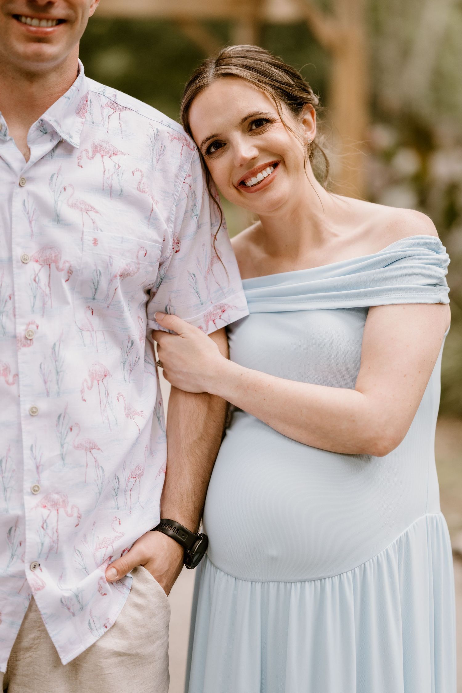 A couple shares playful moments while posing in light blue and floral print clothing.
